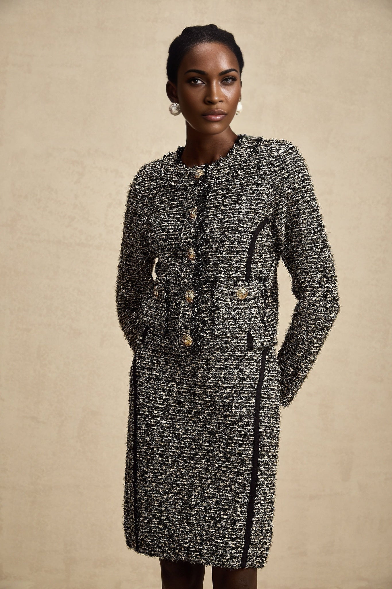 Woman wearing a matching jacket and skirt set in contrasting colors with shimmery lurex fabric details