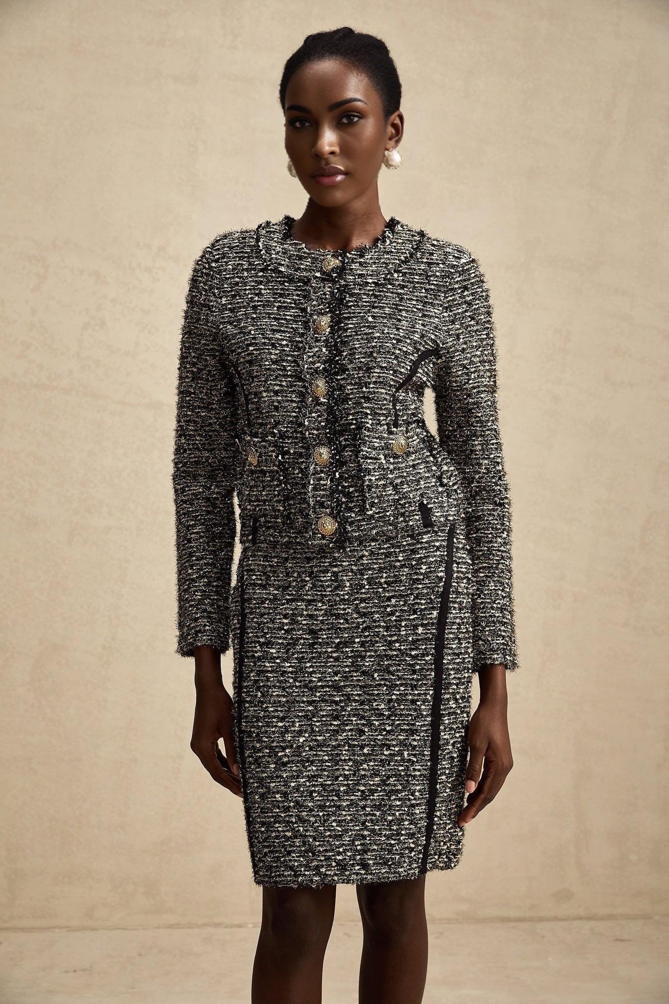 Woman wearing a matching jacket and skirt set with contrasting colors and shimmering lurex fabric details