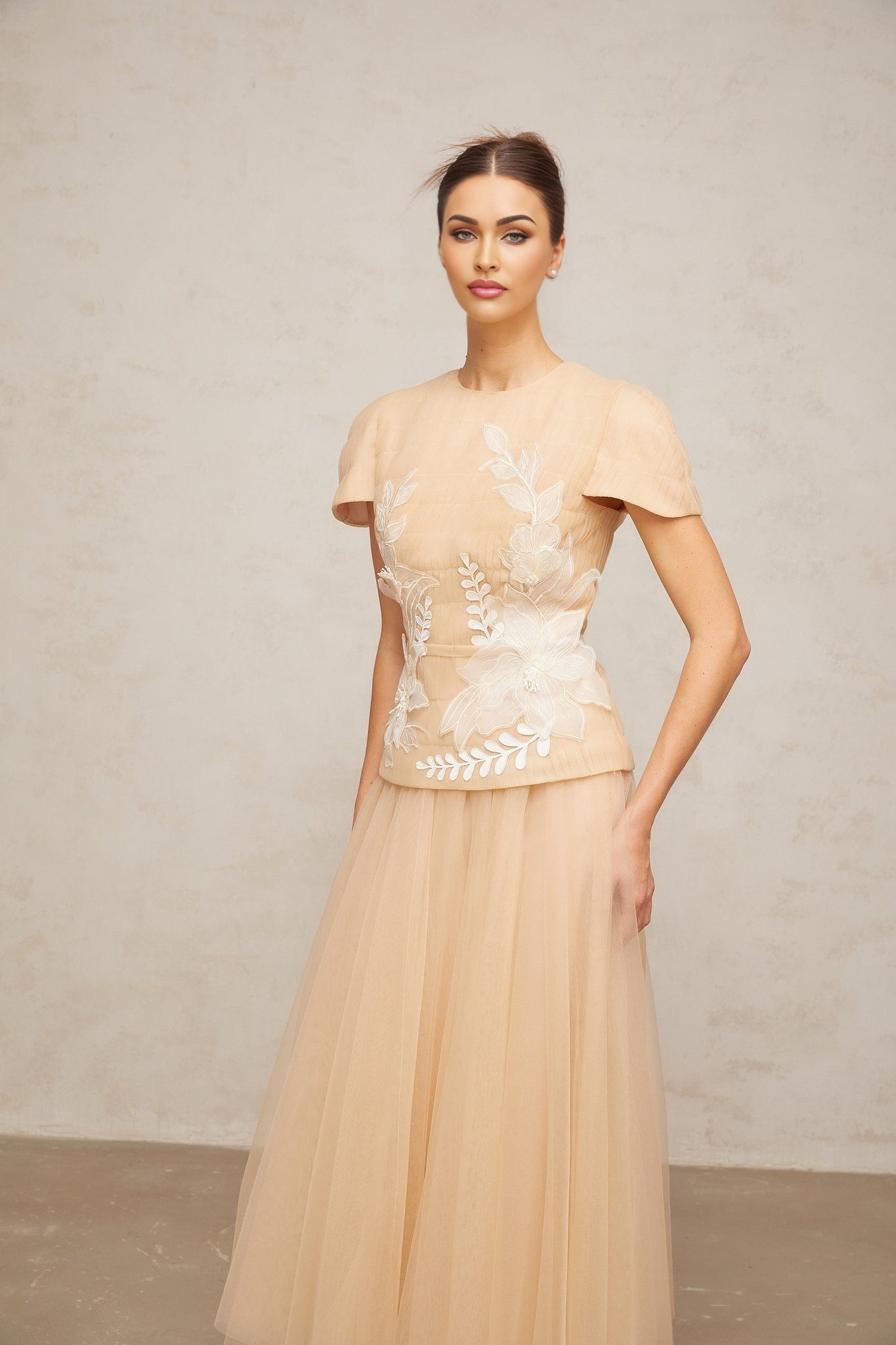 Woman wearing a matching set consisting of a sheer tulle top and skirt adorned with floral appliques in a delicate and romantic style