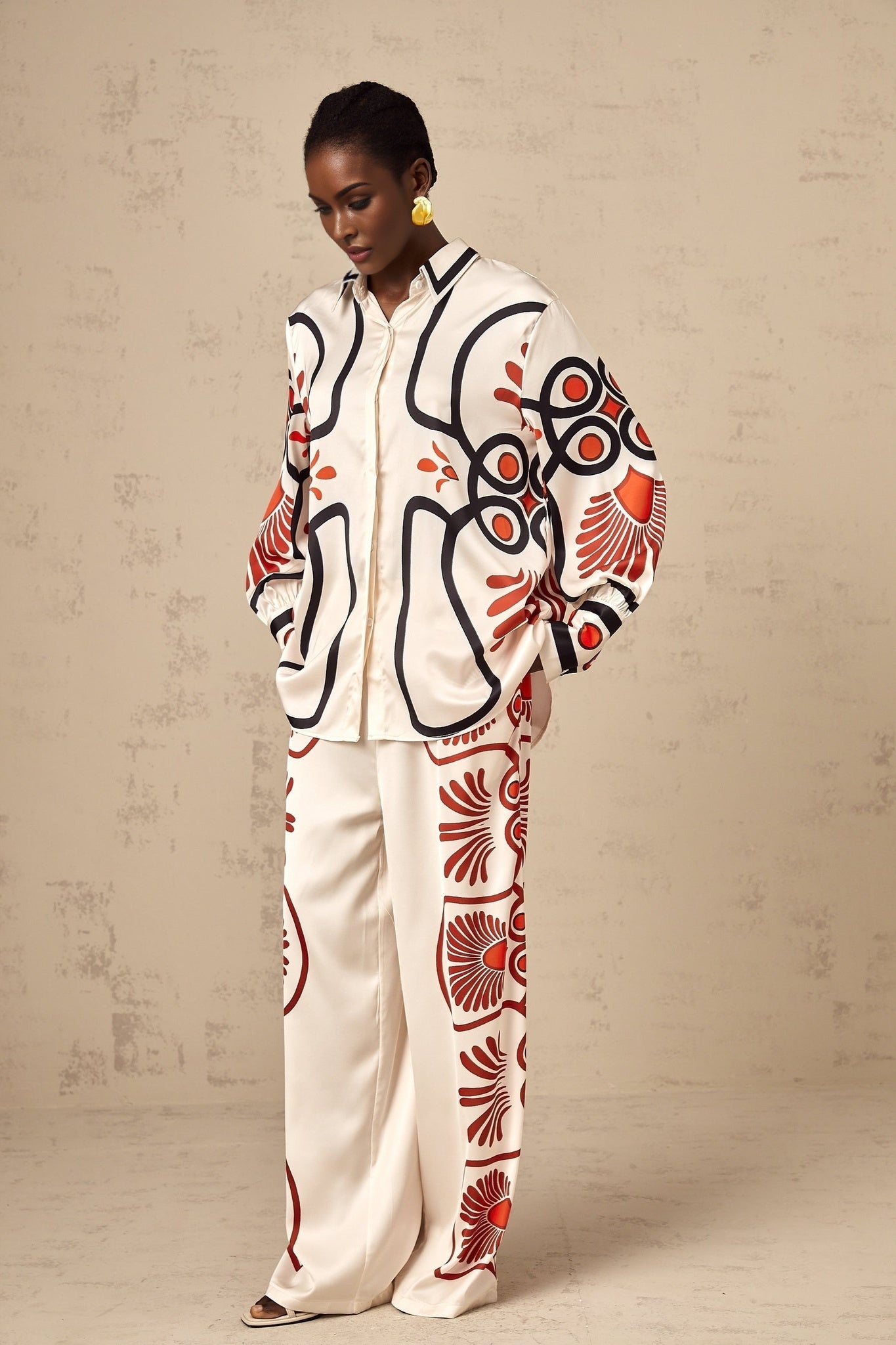 Woman wearing a matching set consisting of a shirt and trousers with a colorful graphic print pattern