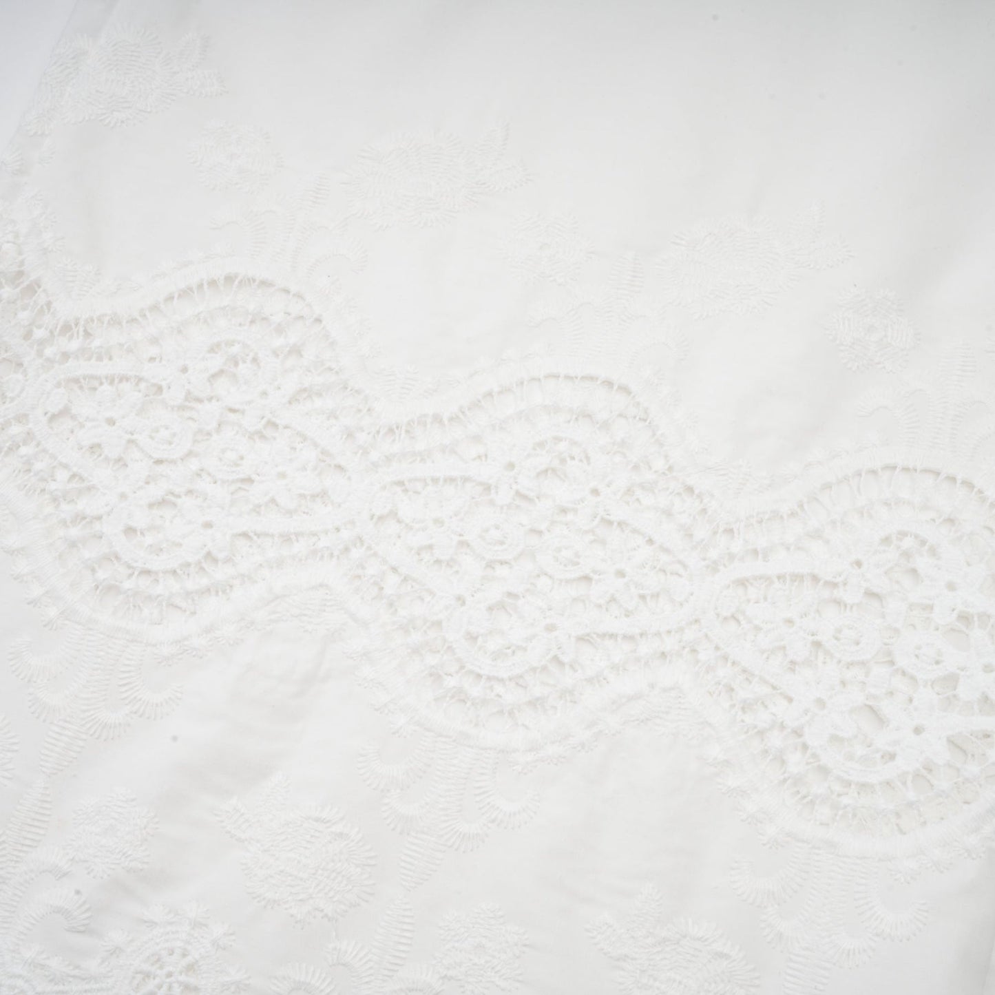 Woman wearing a matching set of white lace trim cropped top and trousers with cutout details