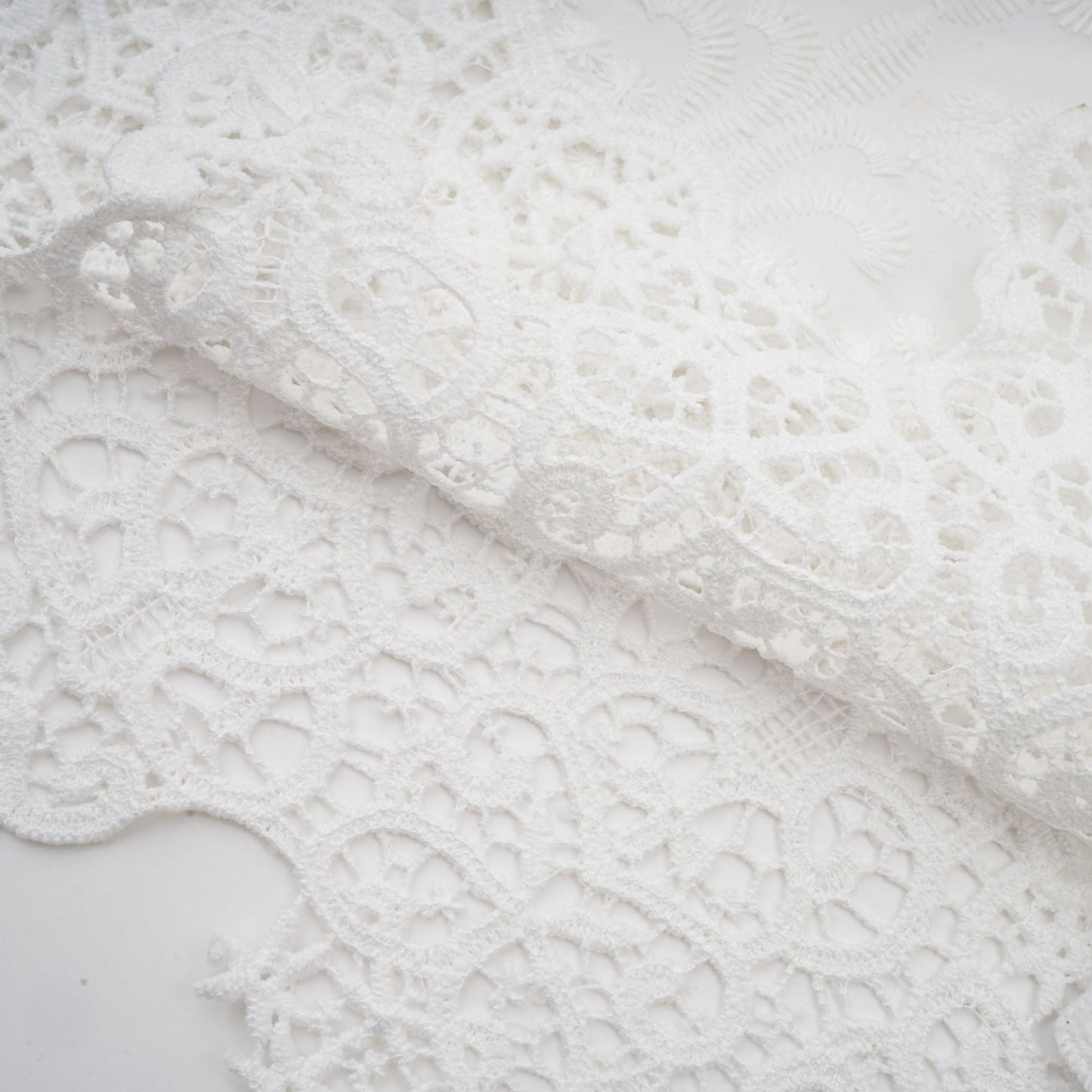 Woman wearing a matching set of white lace trimmed cropped top and trousers with cutout details