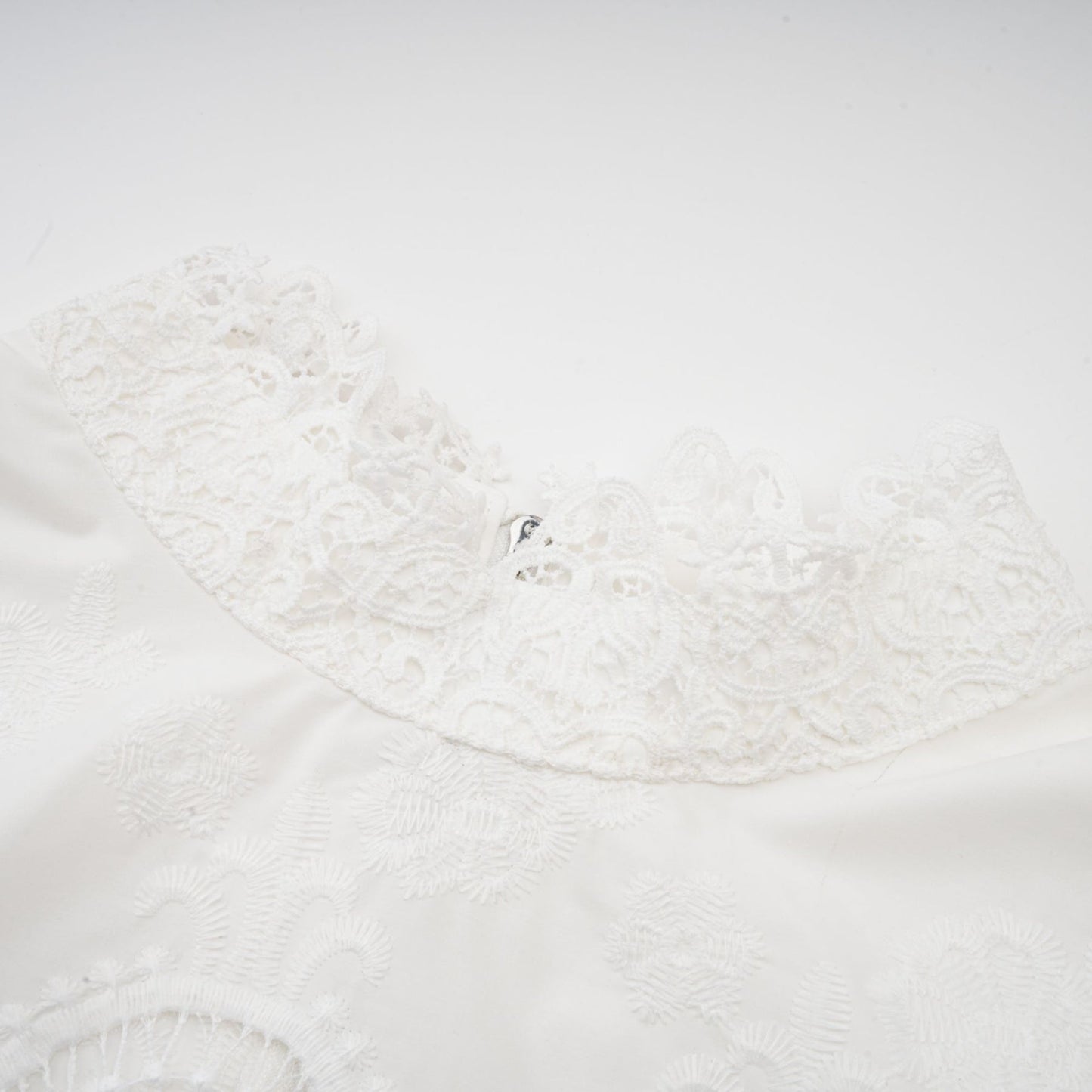 Woman wearing a matching set of white lace trimmed cropped top and trousers with cutout details