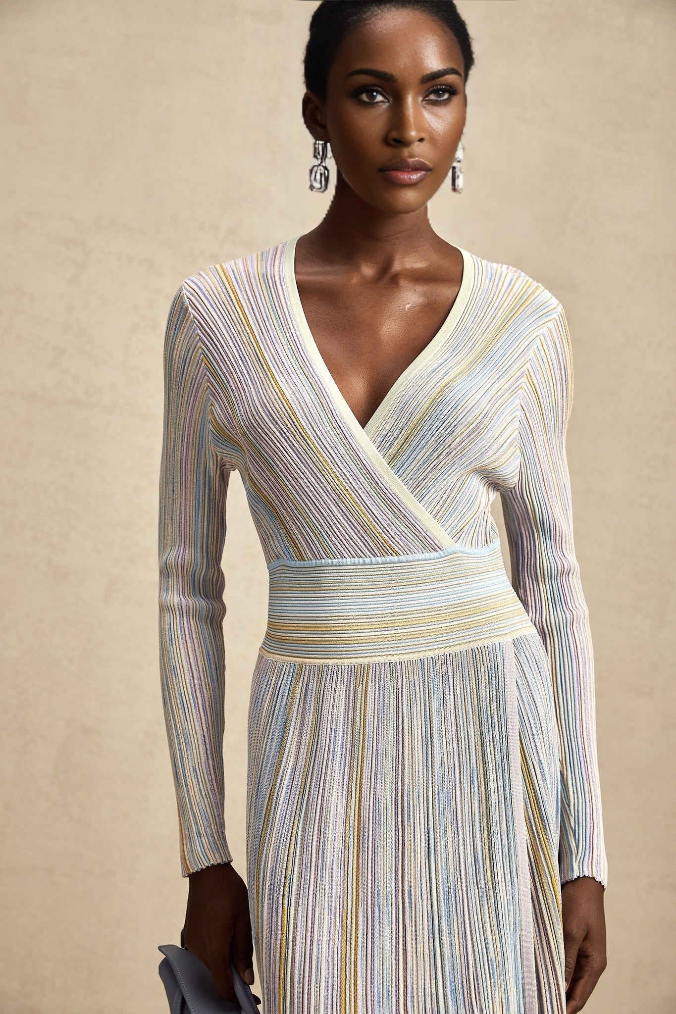 Woman wearing a multicolored vertical striped knit midi dress with long sleeves and a fitted silhouette