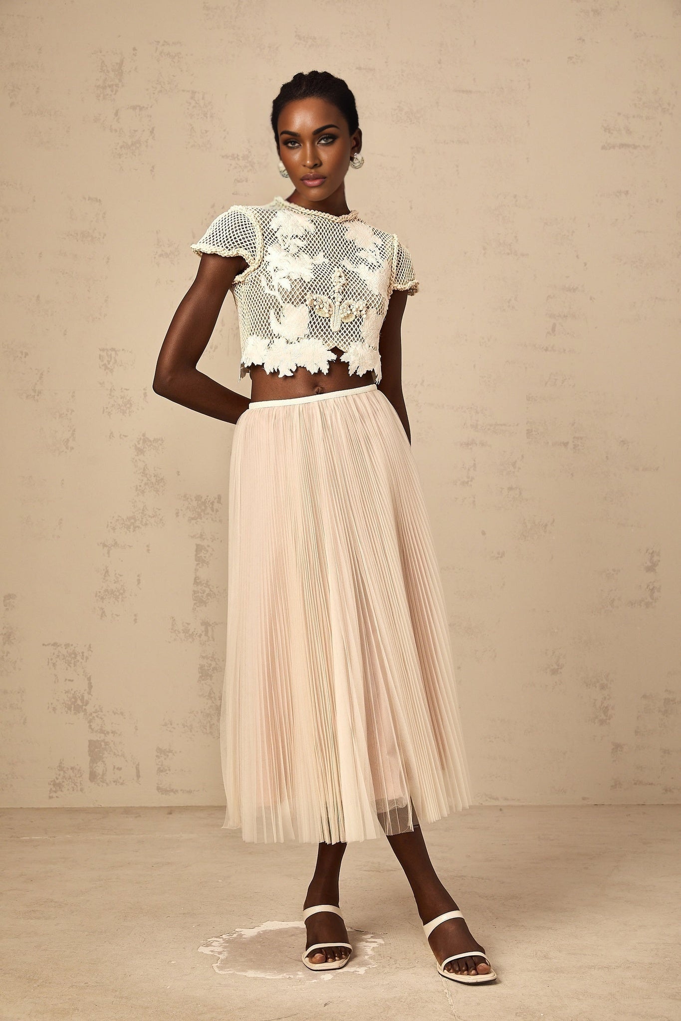 Woman wearing a neutral colored matching top and skirt set with floral applique details