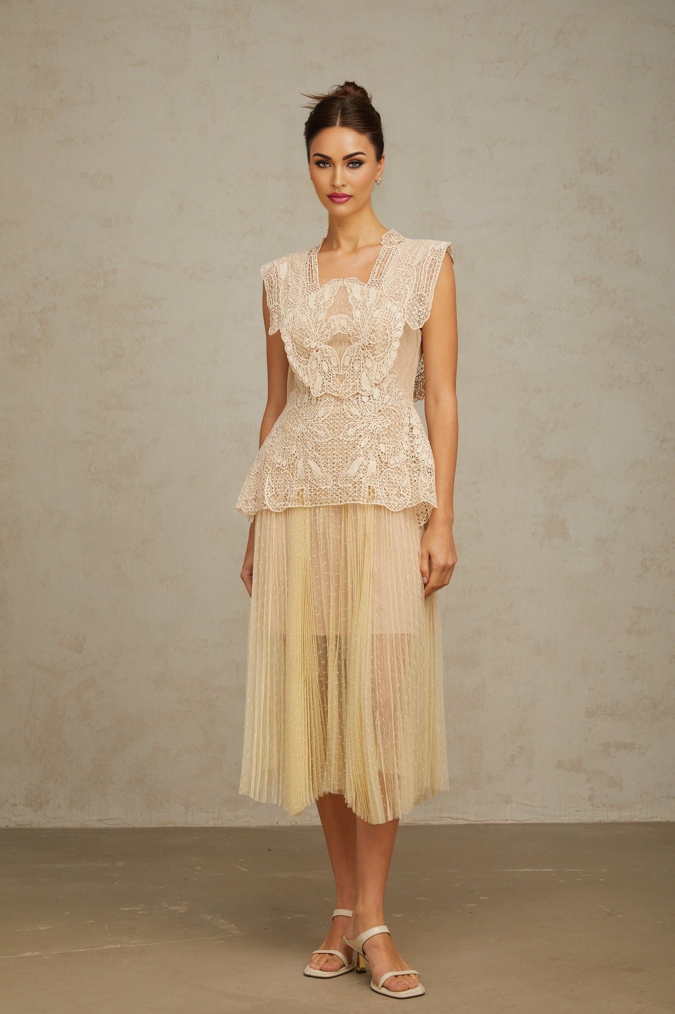 Woman wearing a neutral colored midi dress with floral lace panels and tulle detailing