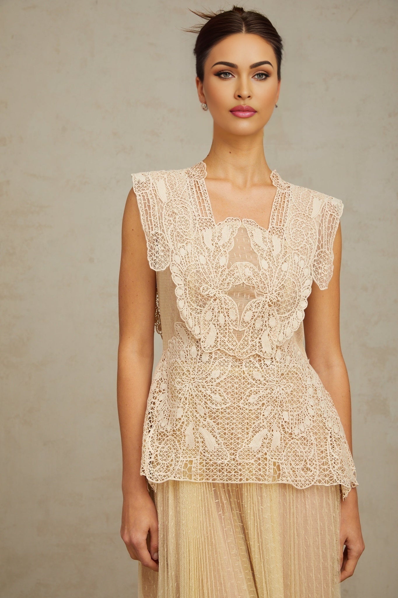 Woman wearing a neutral colored midi dress with floral lace panels and tulle fabric