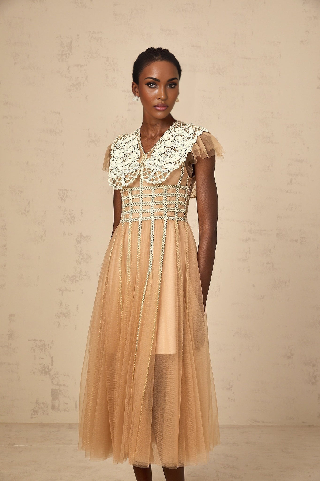 Woman wearing a neutral colored midi dress with lace panels and tulle skirt