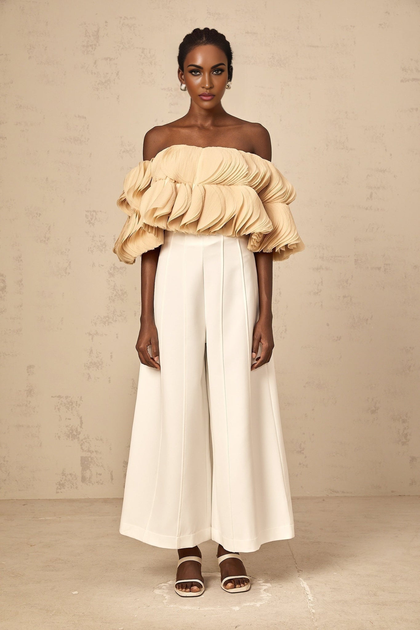 Woman wearing a neutral colored off shoulder cropped top with shirred detailing