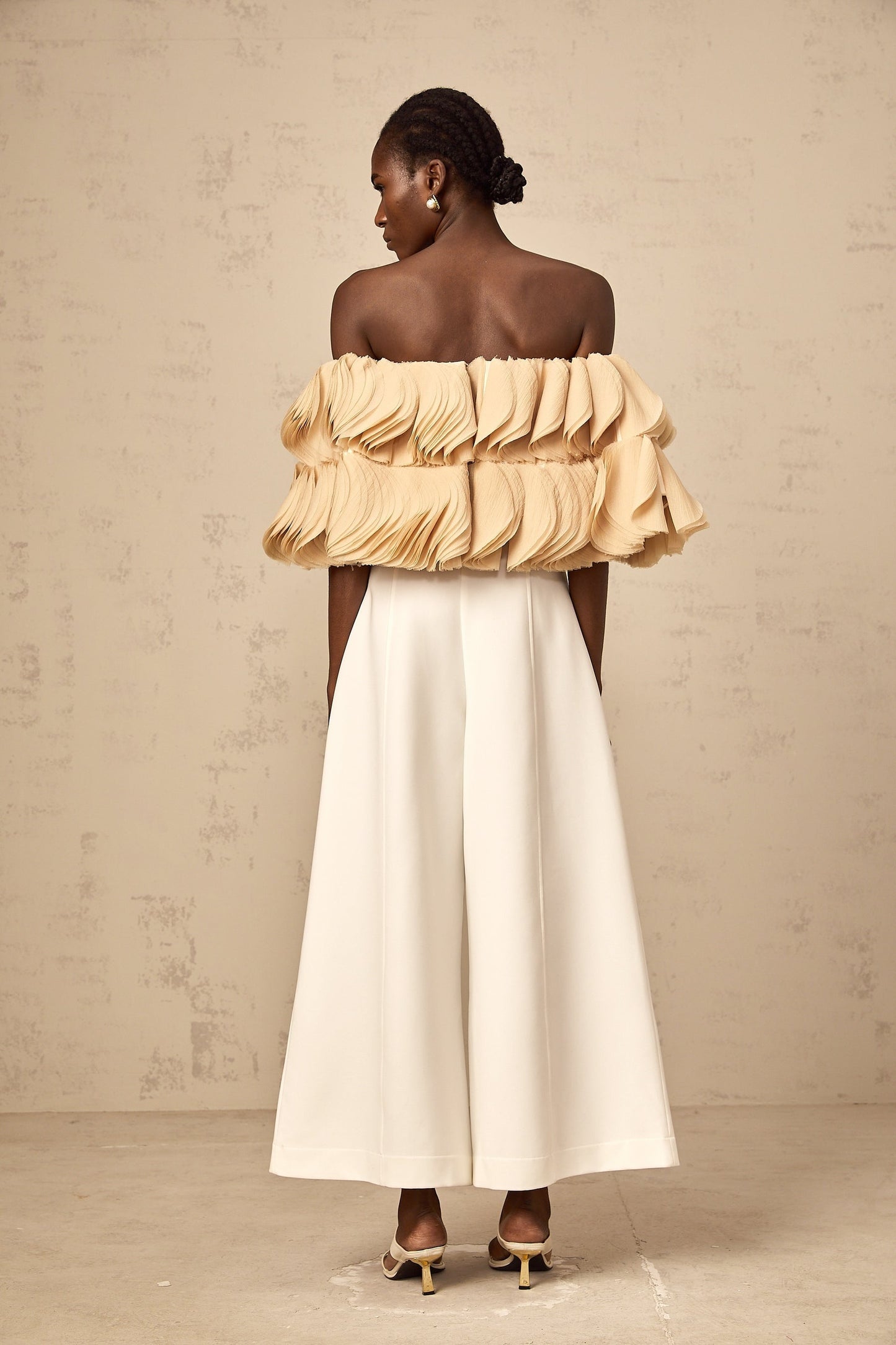 Woman wearing a neutral colored offshoulder cropped top with shirred detail