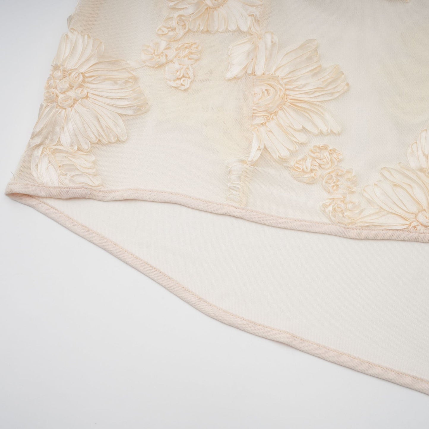 Woman wearing a neutral colored offshoulder maxi dress with embroidery details standing in a relaxed pose