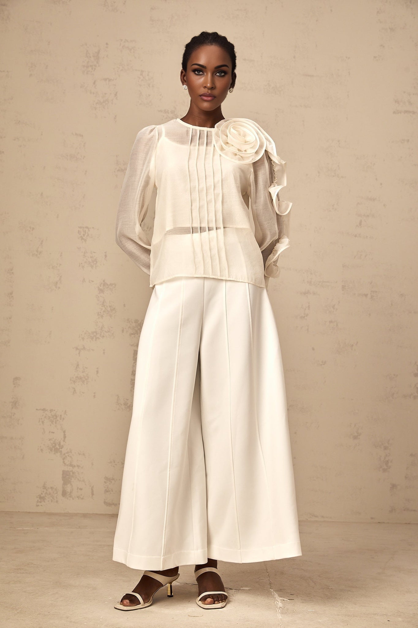 Woman wearing a neutral colored semi sheer blouse with delicate 3d flower details