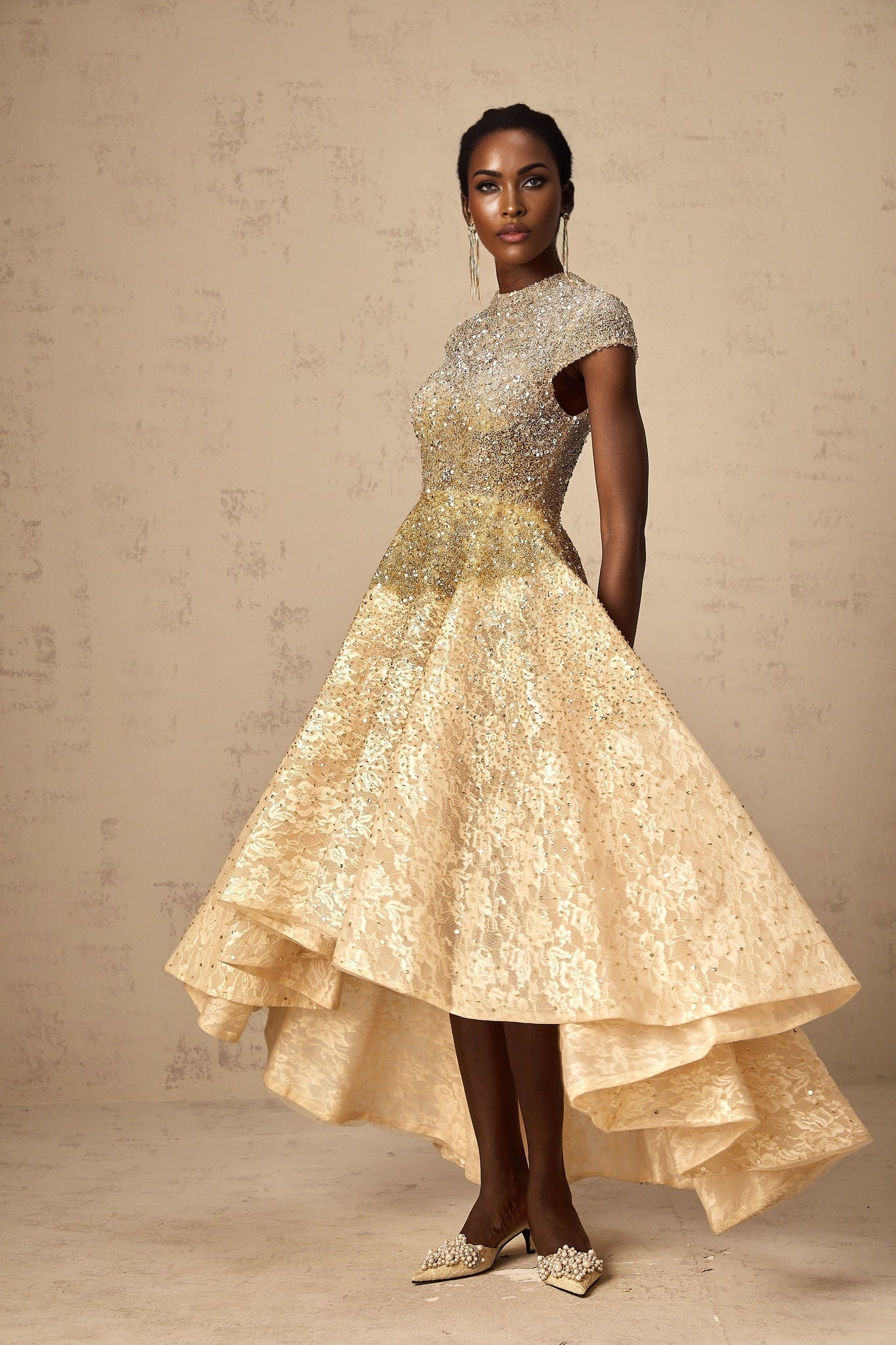 Woman wearing a neutral colored sequined dress with high low hemline