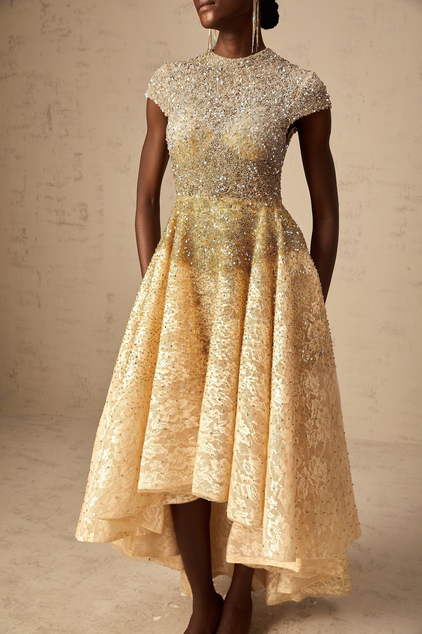 Woman wearing a neutral colored sequined dress with high low hemline
