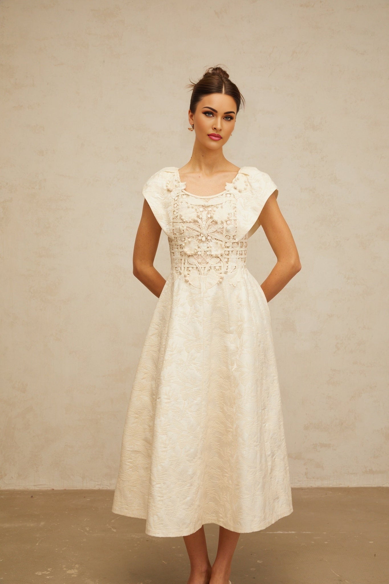 Woman wearing a neutralcolored midi dress with floral embroidery and embellishments