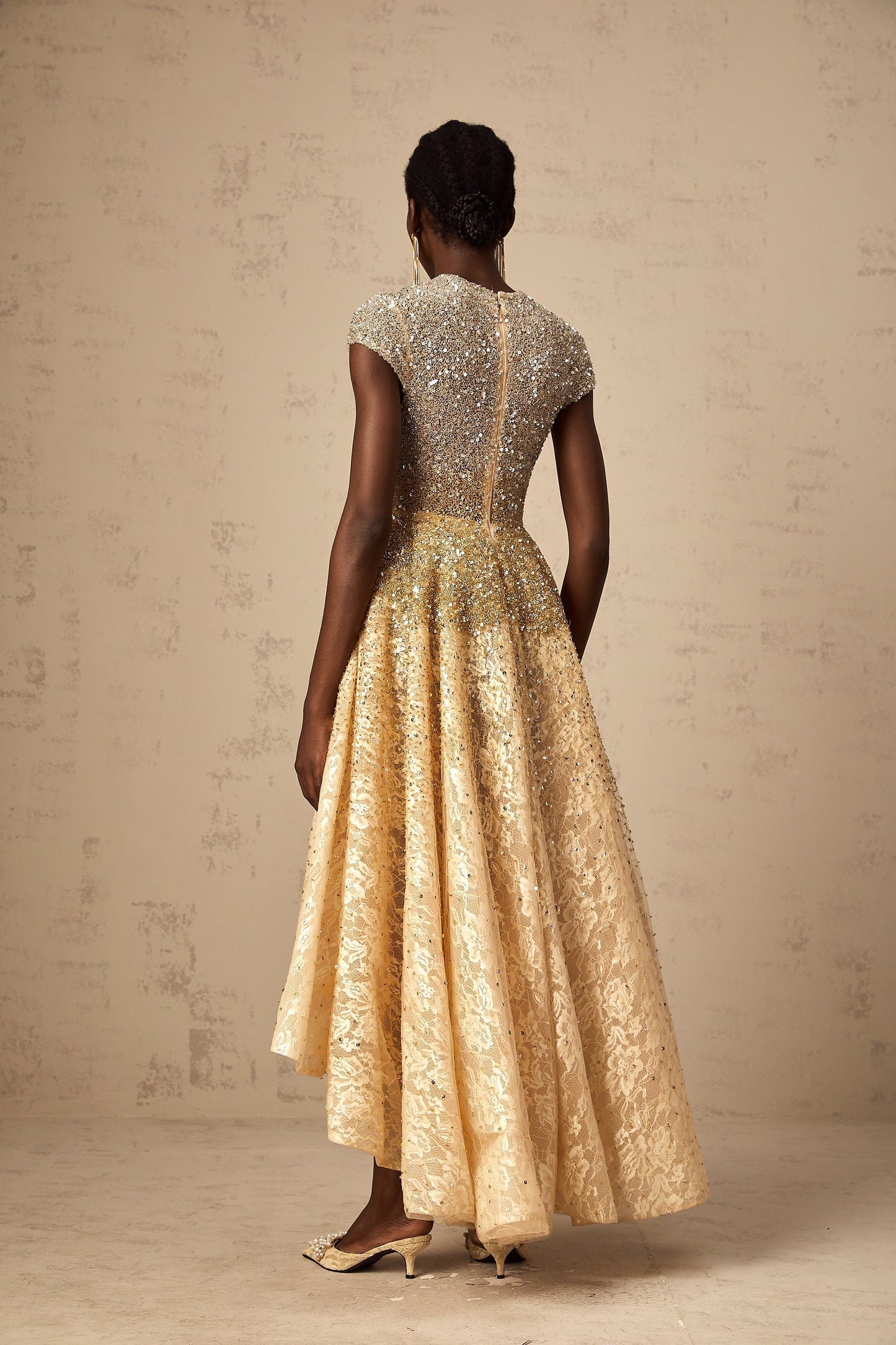Woman wearing a neutralcolored sequined dress with a highlow hemline