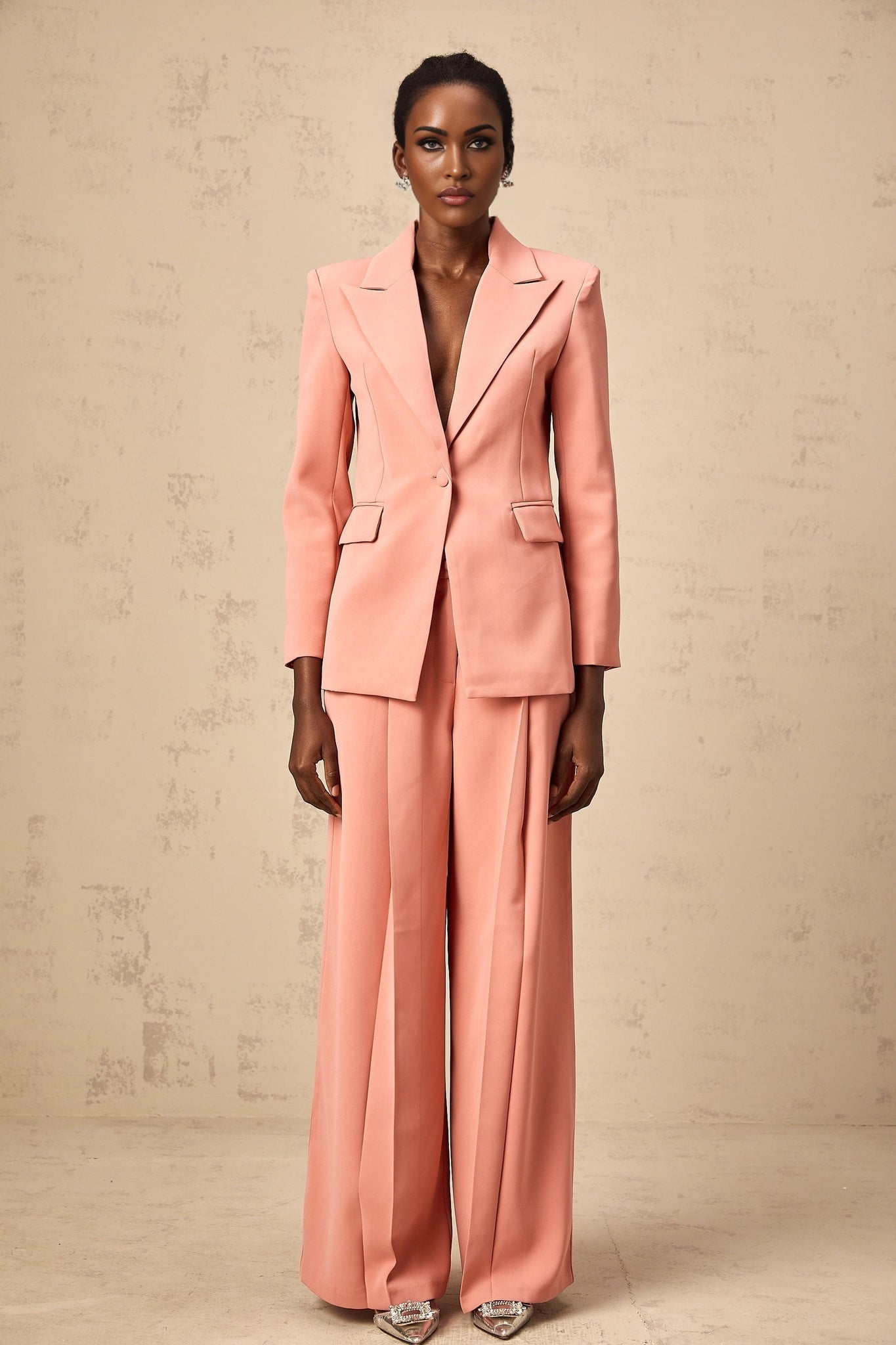 Woman wearing a pink blazer and trousers set with embroidery details and cutout design