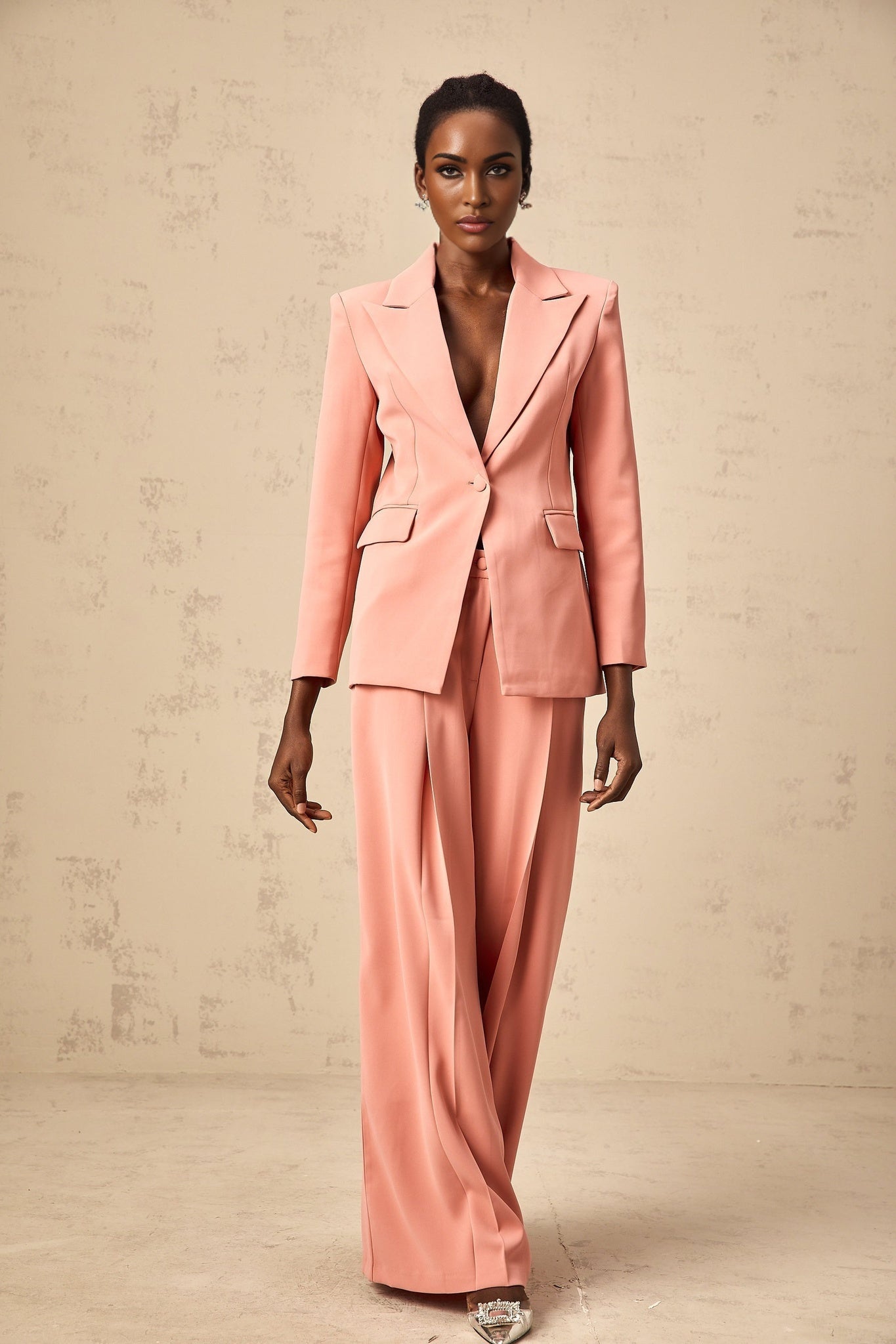 Woman wearing a pink blazer and trousers set with embroidery details and cutout design