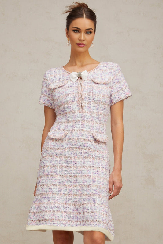 Woman wearing a purple and white checked knit midi dress with long sleeves and a fitted silhouette standing against a plain background