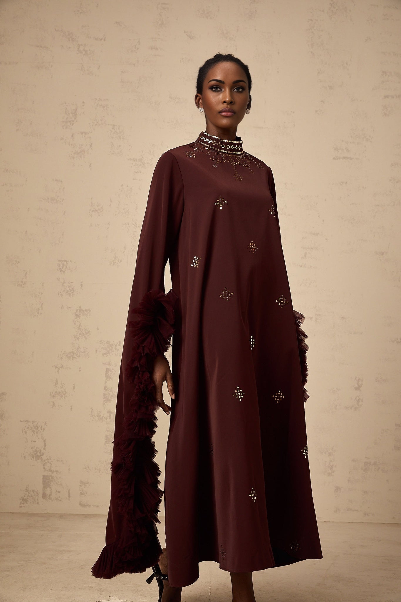 Woman wearing a purple midi dress with sequin embellishments and flared sleeves