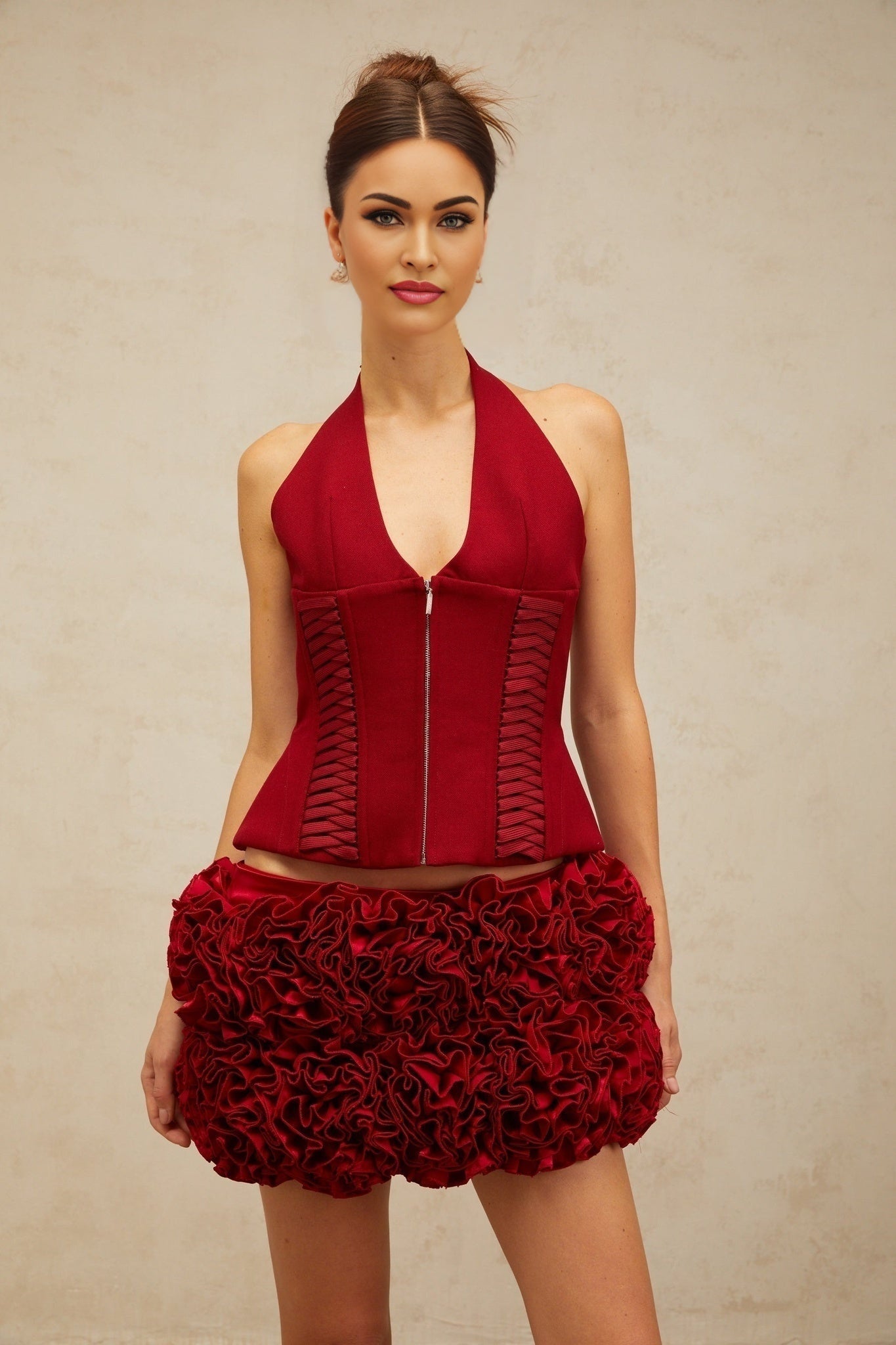 Woman wearing a red halterneck top with lace up detail