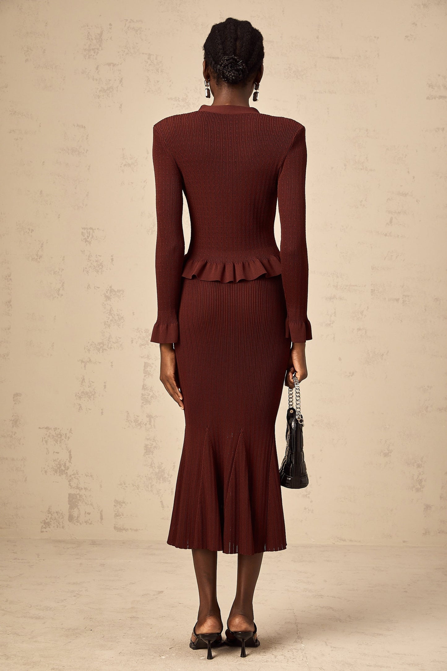 Woman wearing a red knit top with ruffles and matching skirt set named Corrine