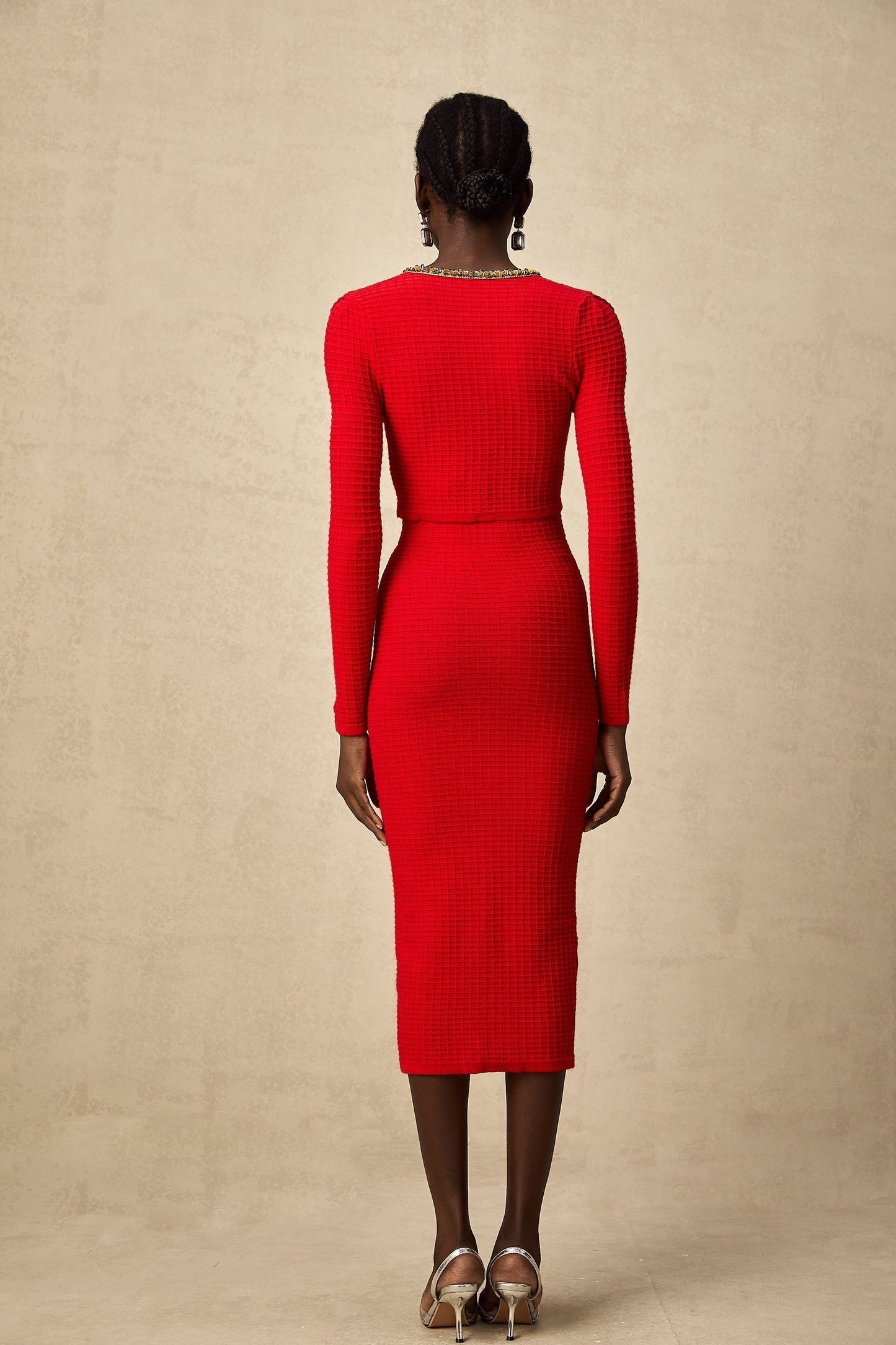 Woman wearing a red knitted cardigan and matching skirt set with embellishments named Axelle