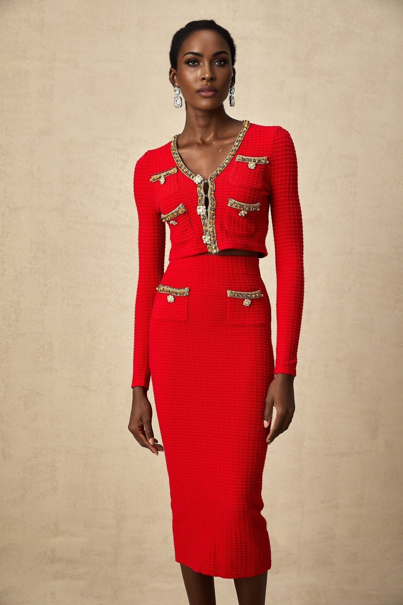 Woman wearing a red knitted cardigan and matching skirt set with embellishments named Axelle