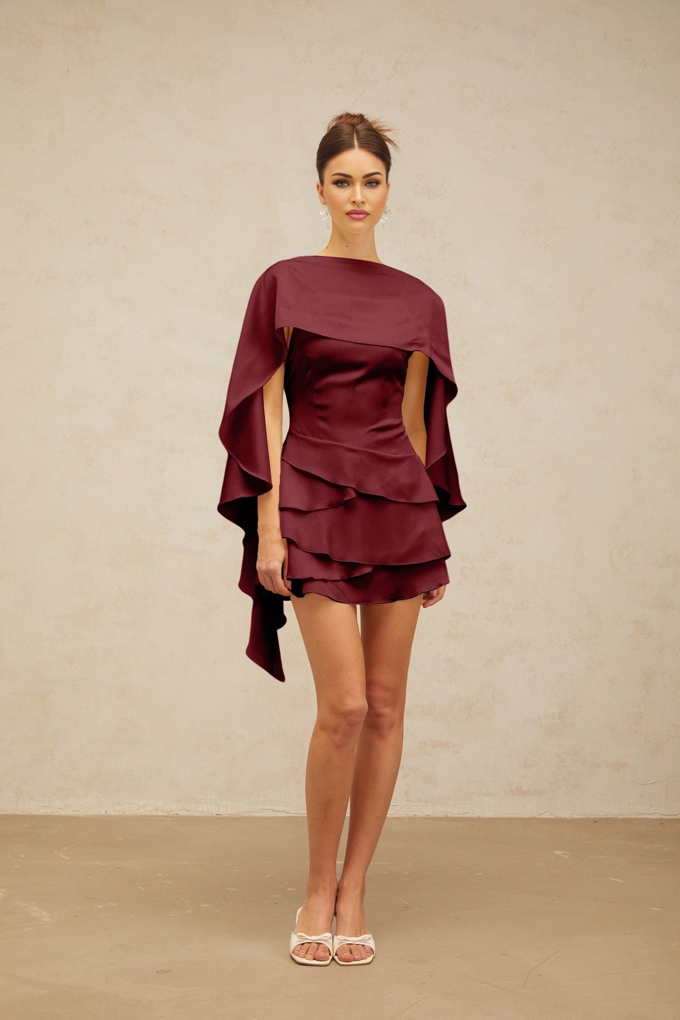 Woman wearing a red satin mini dress with shawl panel and ruffled details