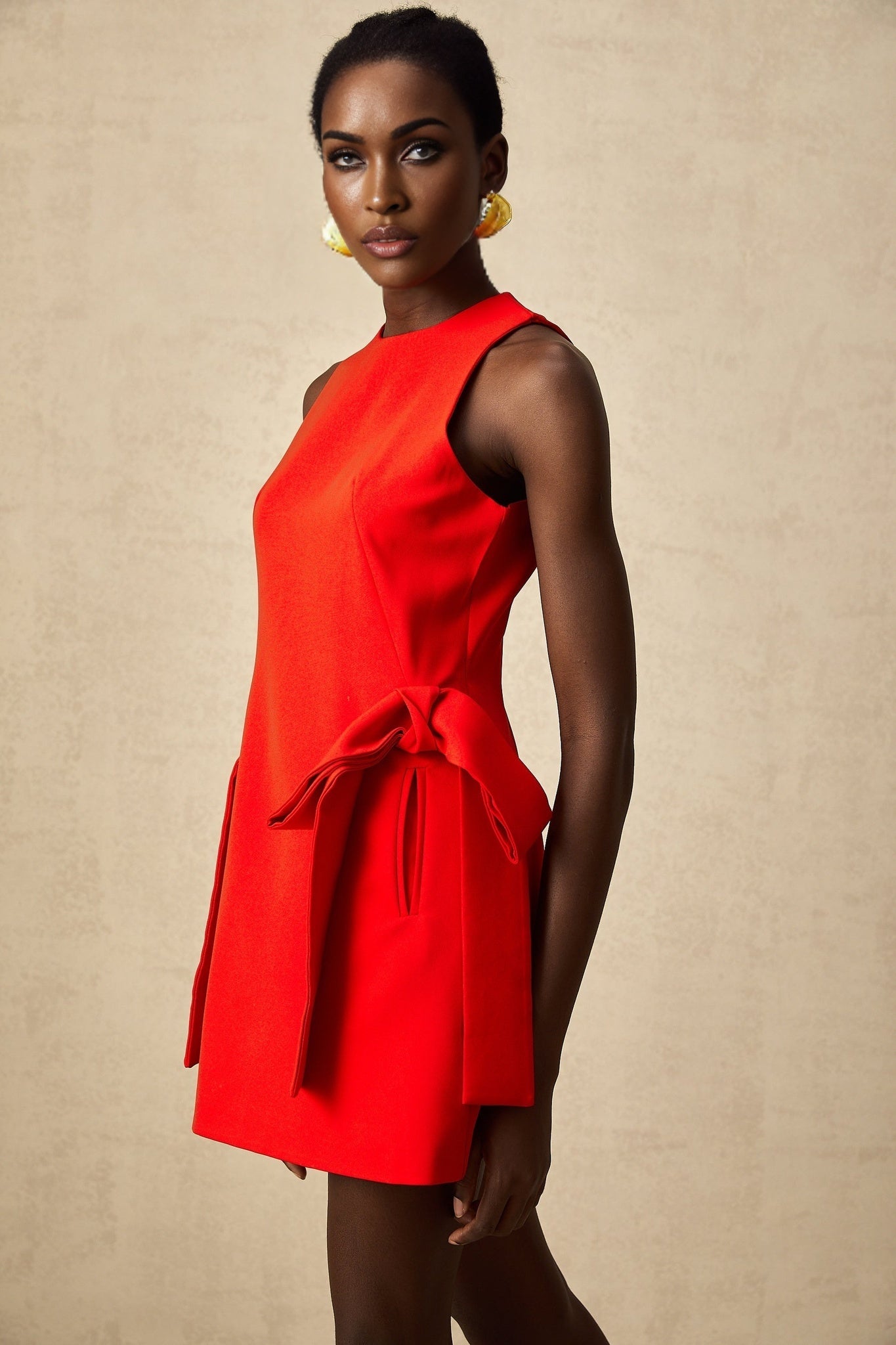 Woman wearing a red sleeveless mini dress with a bow detail