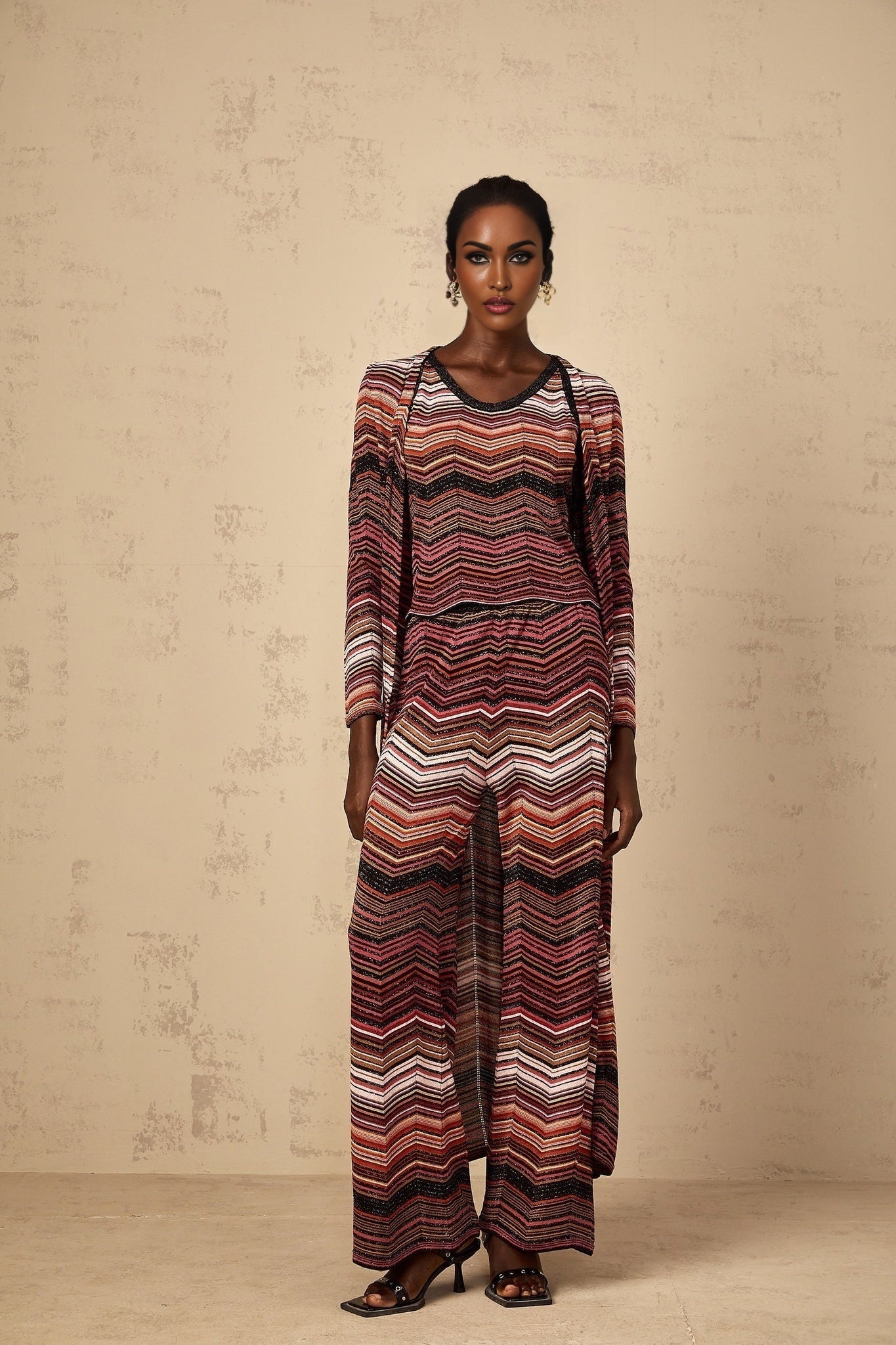 Woman wearing a red striped long knit cardigan by Chloe standing in a neutral background