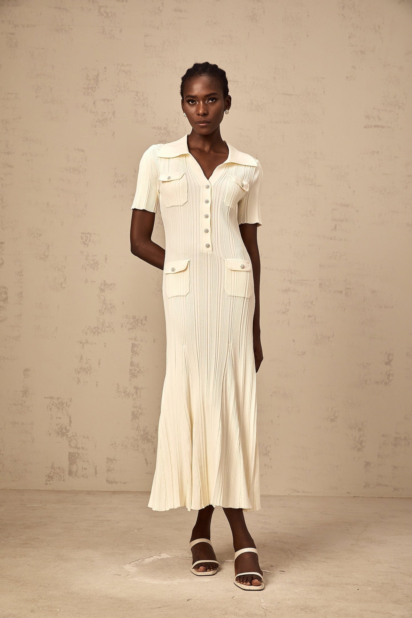 Woman wearing a ribbed knit midi dress in neutral tones standing in a relaxed pose
