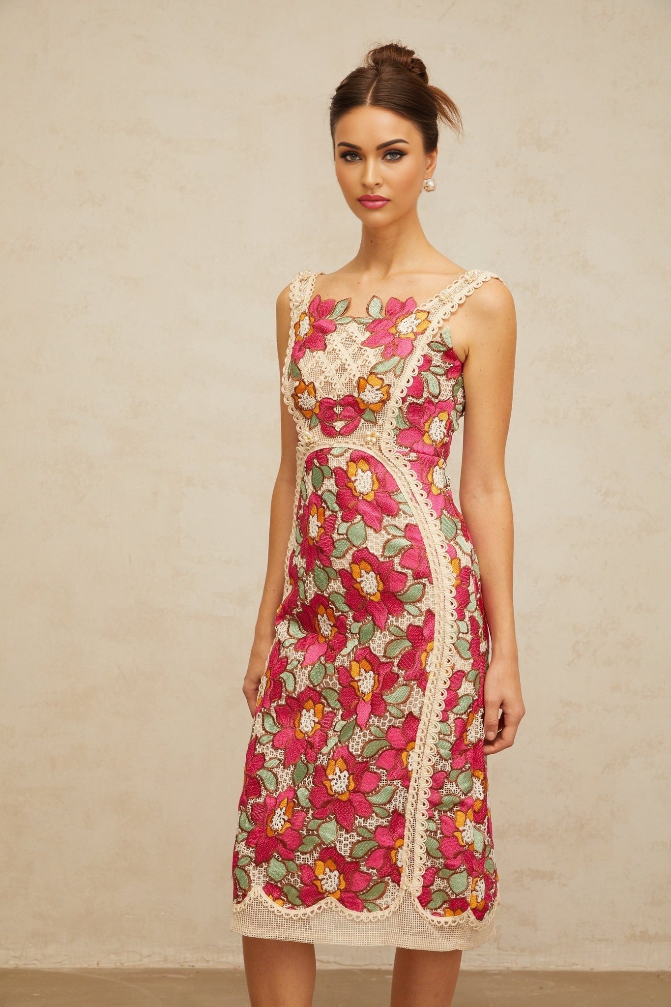 Woman wearing a rosepink midi dress with braided details and floral embroidery Nalini design