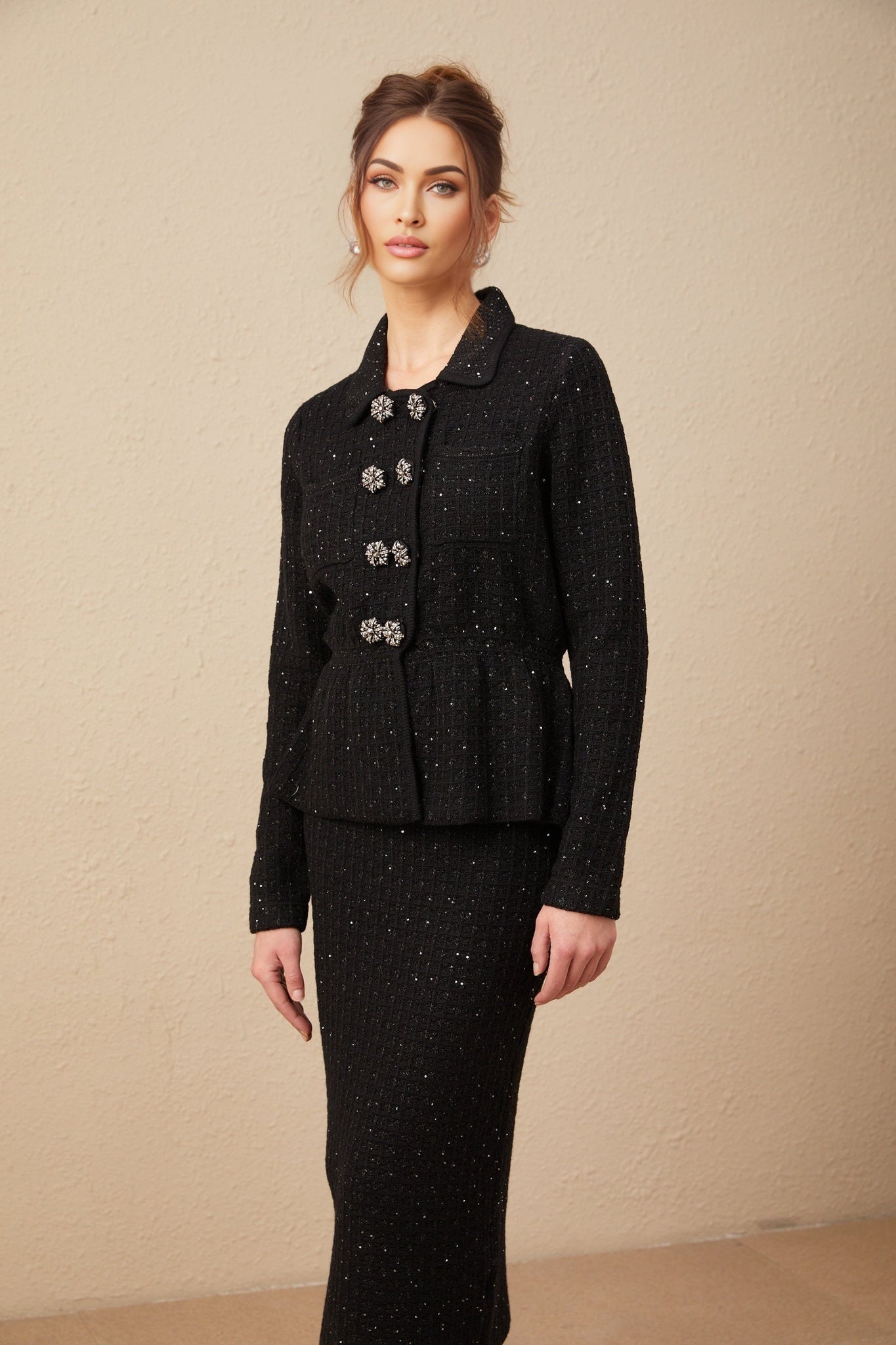 Woman wearing a shimmering sequined waffle knit jacket and matching skirt set in a light color