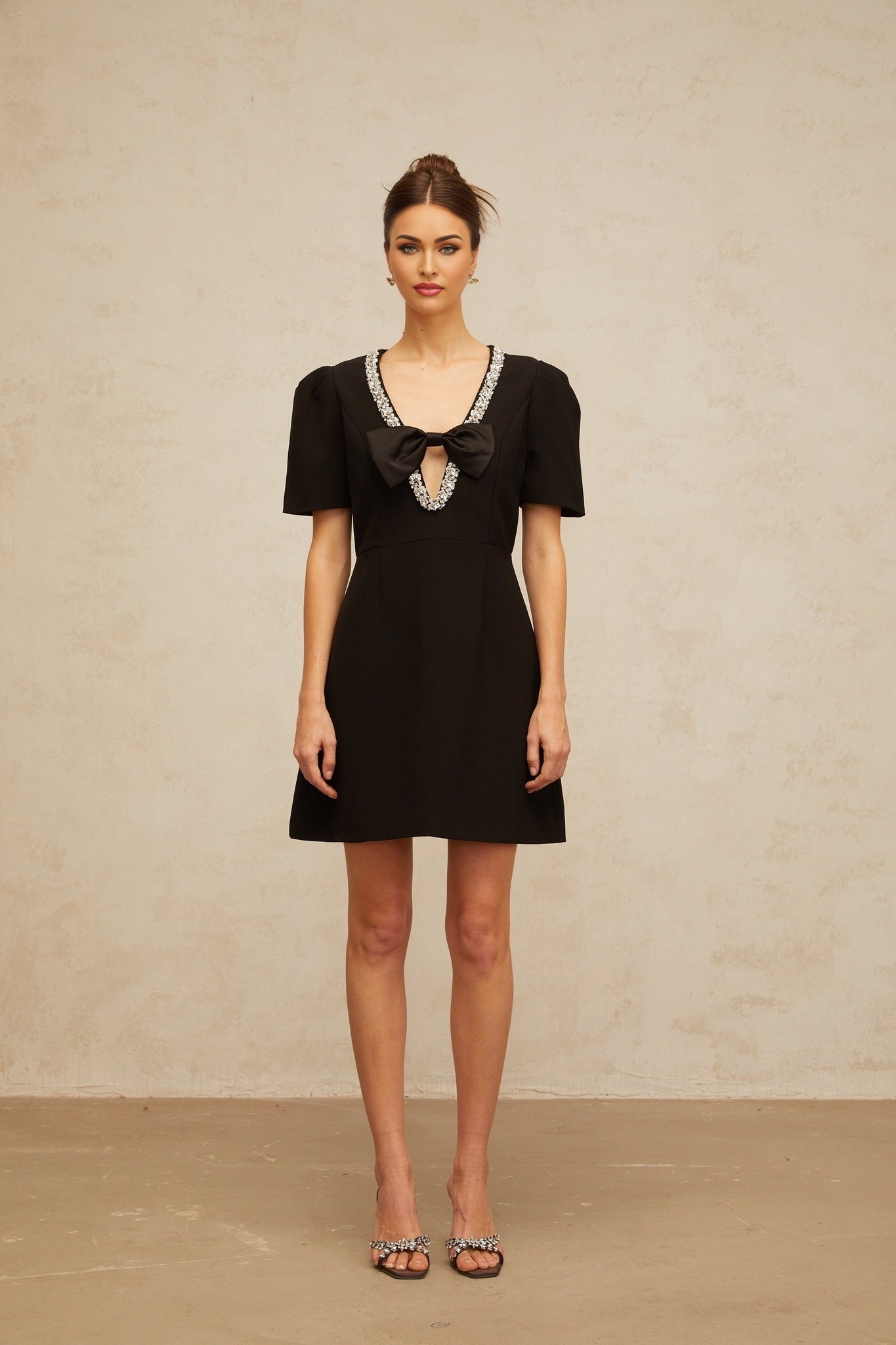 Woman wearing a short black dress with bow detail