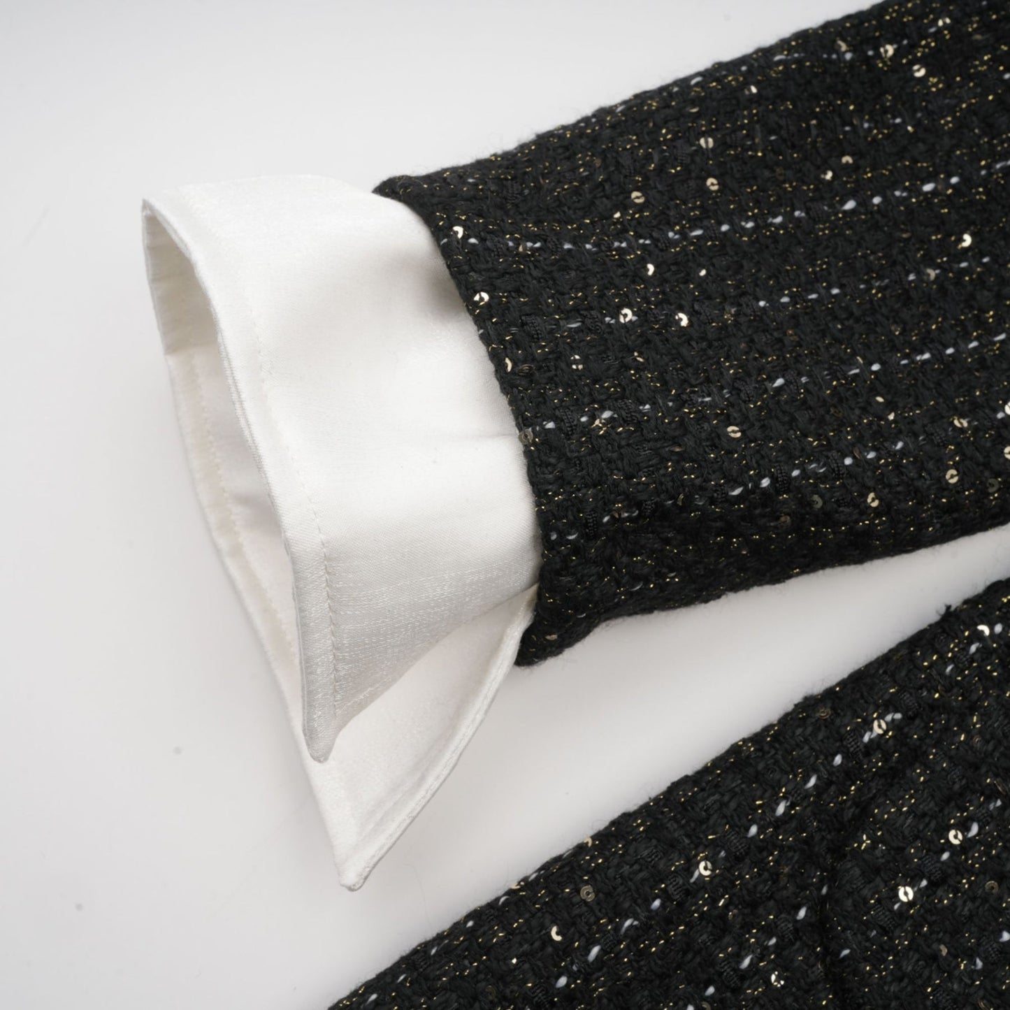 Woman wearing a short black dress with tweed fabric and sequin panels