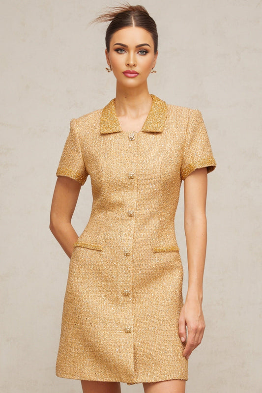 Woman wearing a short gold dress with sequin embellishments and tweed texture