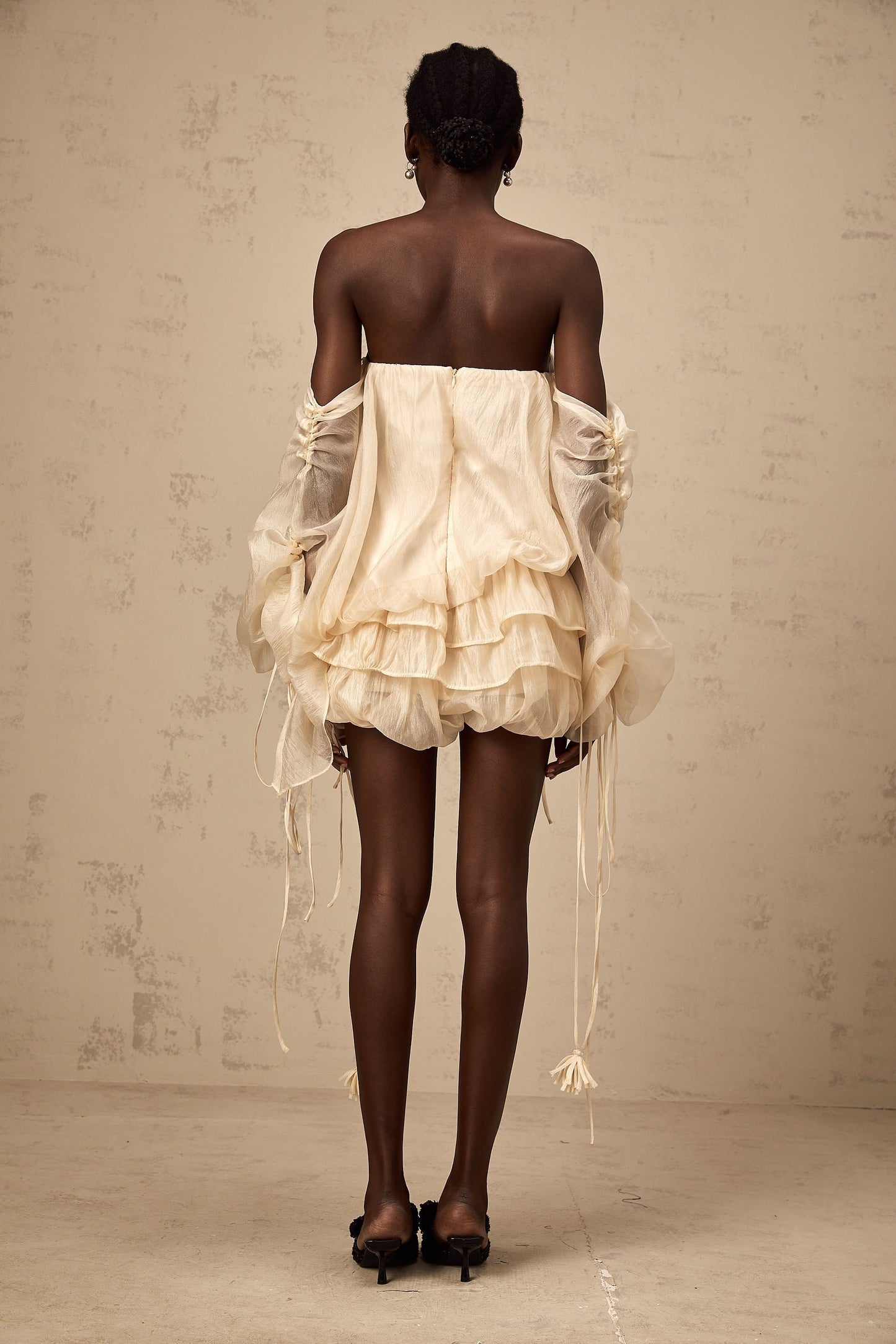 Woman wearing a short offshoulder dress with ruched detailing and layered fabric in a selftie style