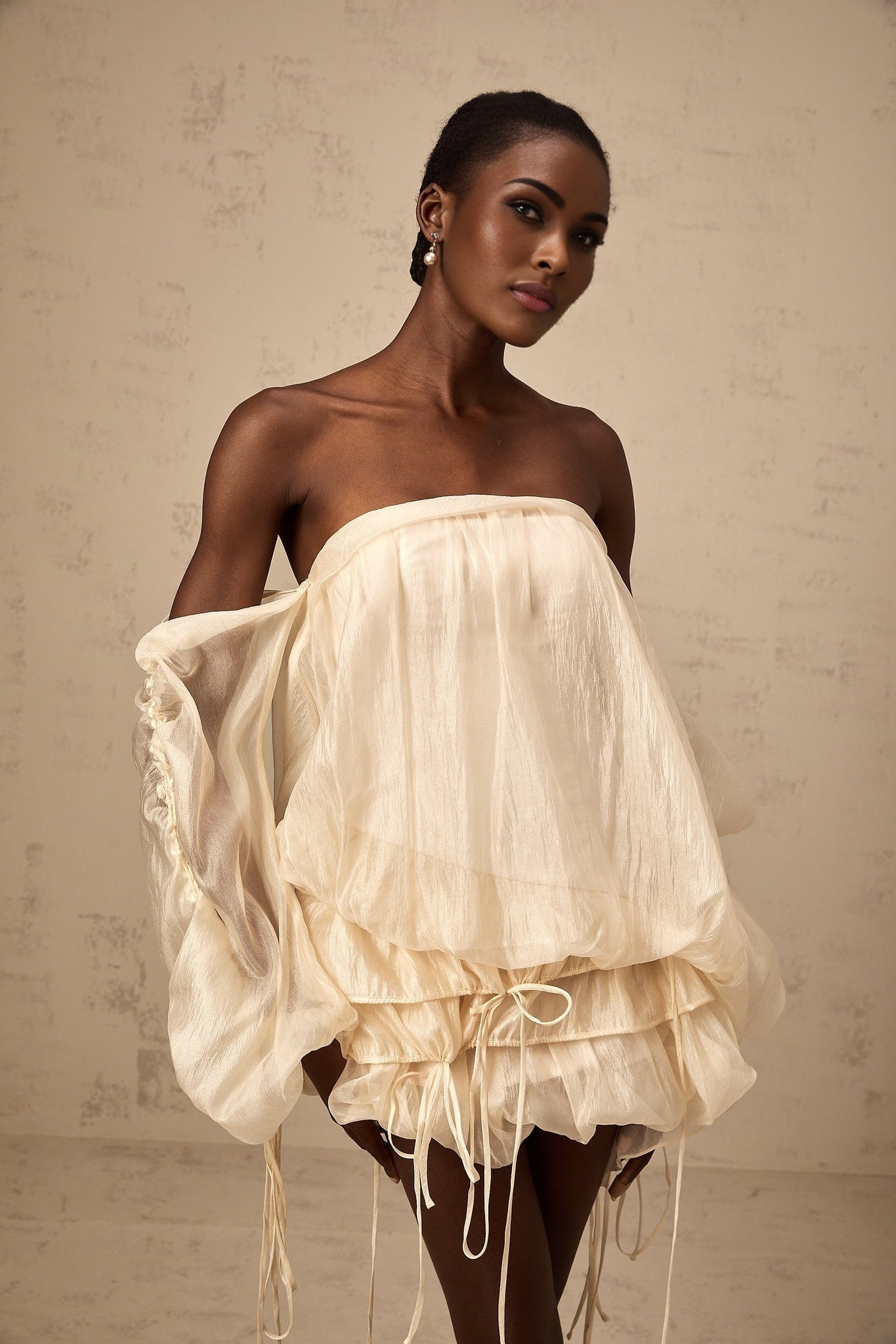 Woman wearing a short offshoulder dress with ruched detailing and selftie feature in layered design