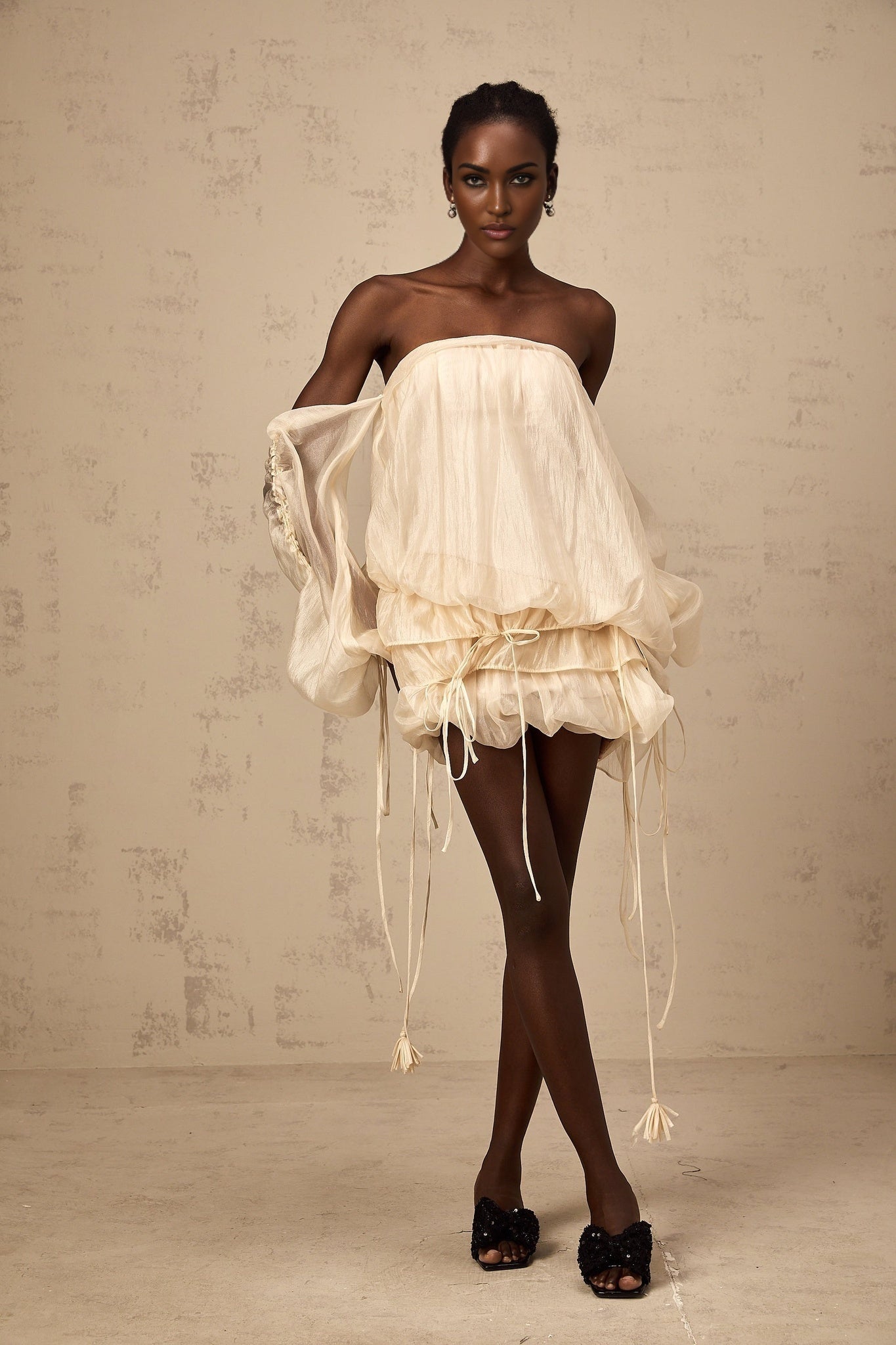 Woman wearing a short offshoulder mini dress with ruched details and selftie straps in a layered design