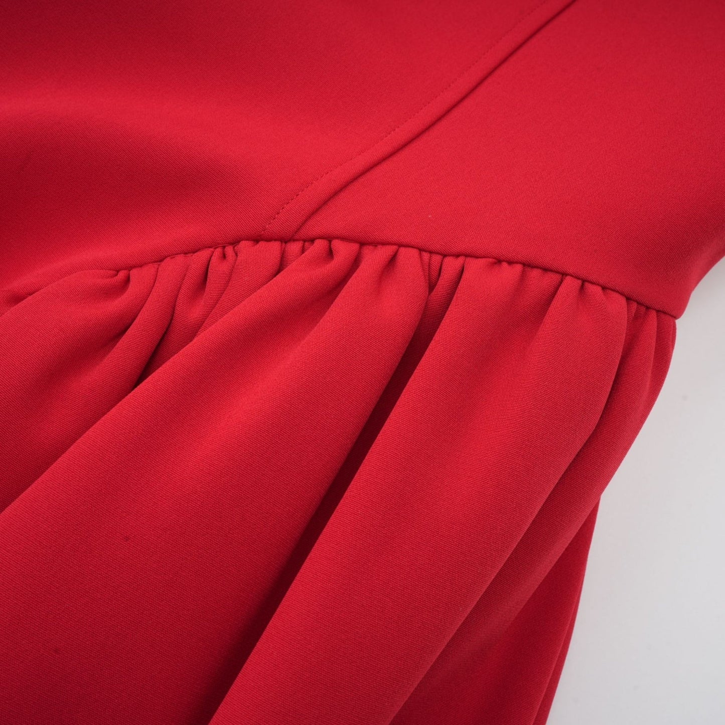 Woman wearing a short red dress with pleated skirt and embellished details