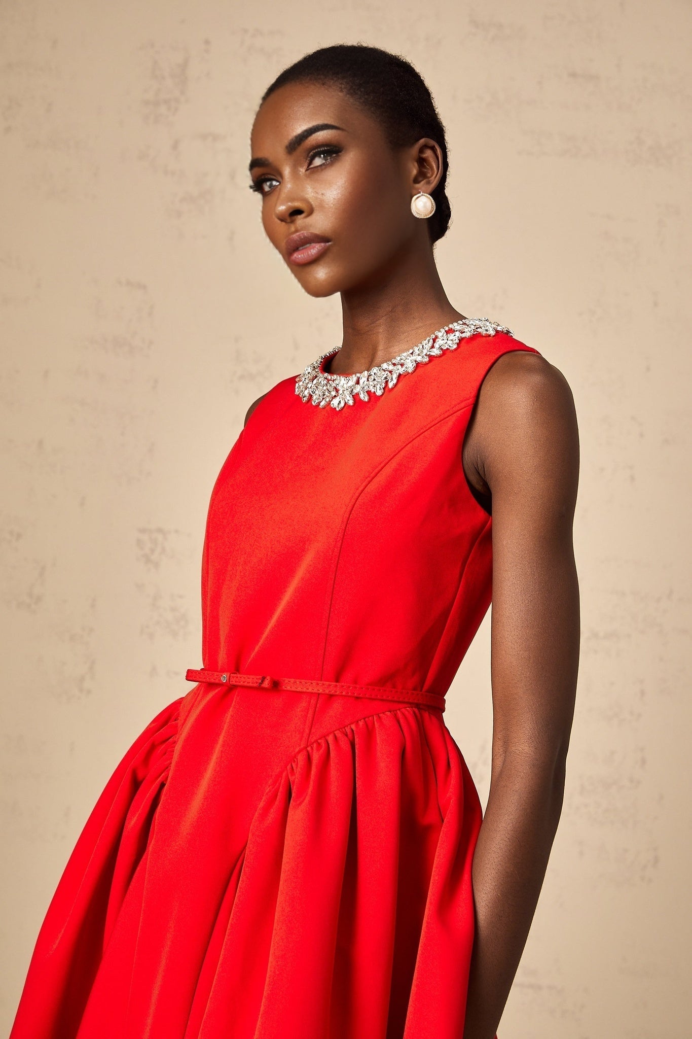 Woman wearing a short red dress with pleats and embellishments