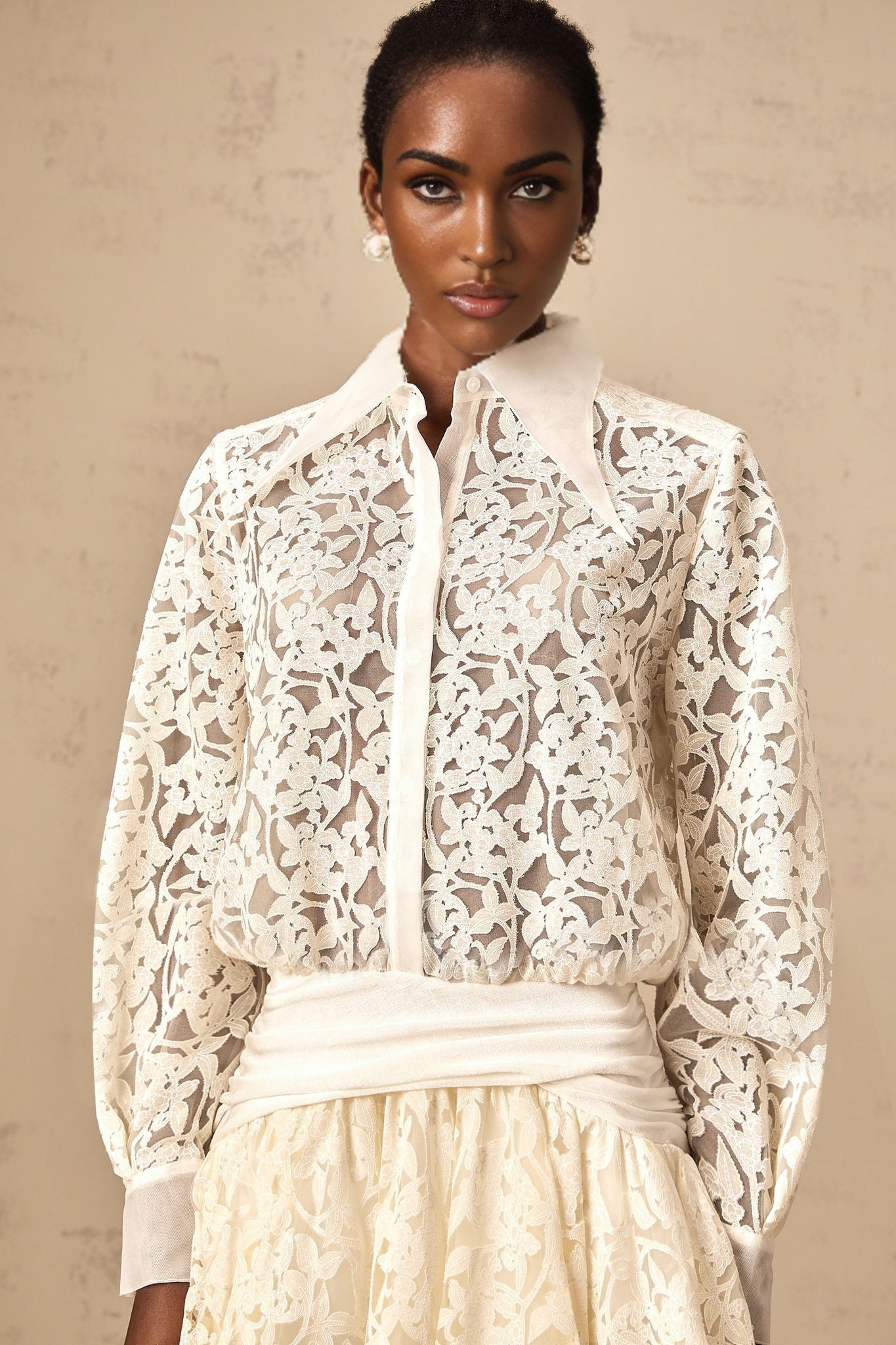 Woman wearing a short white lace dress with floral pattern and shirt collar design