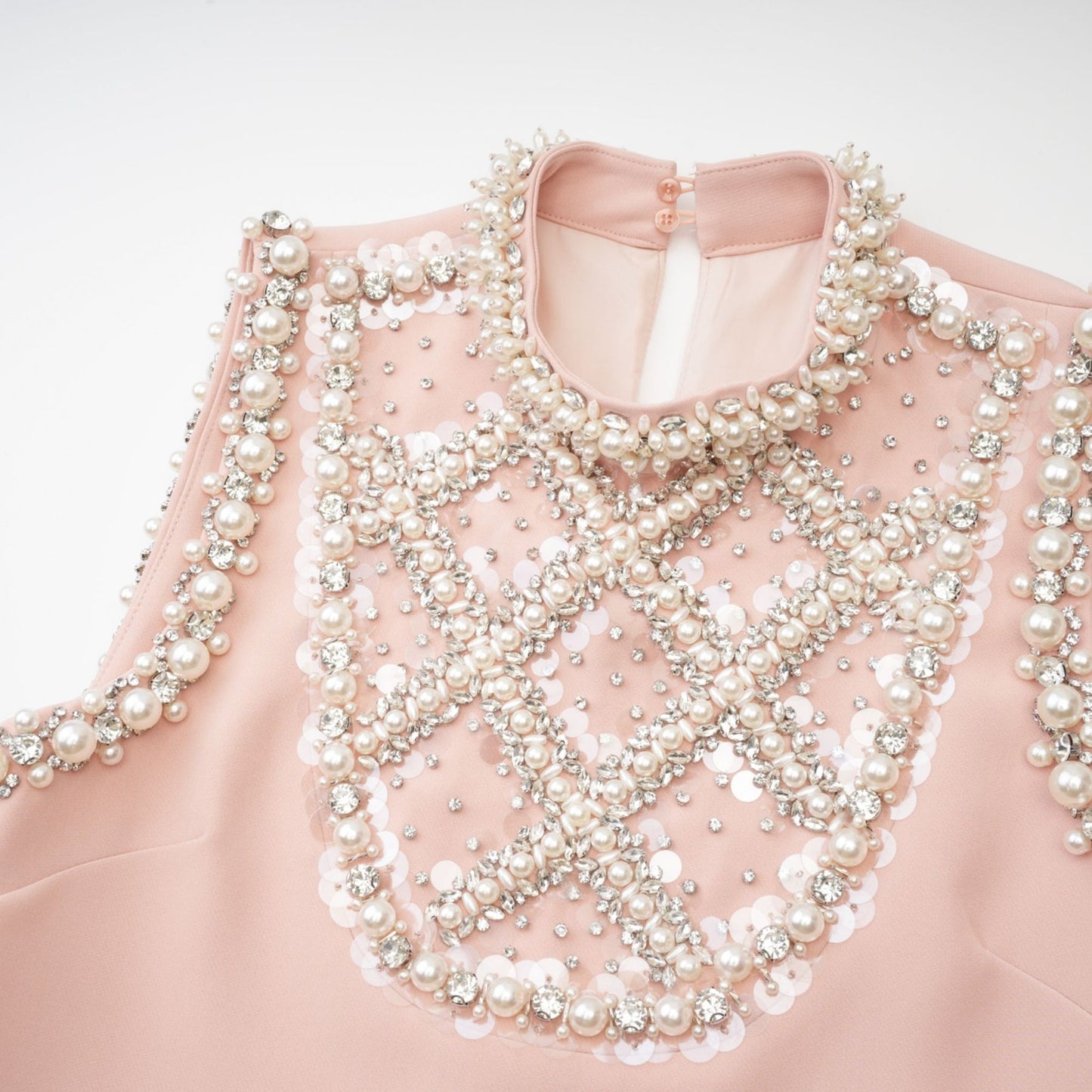 Pink sleeveless dress with crystal embellishments faux pearls and a round neck Fastened at the rear cut at thigh length Made of 80% polyester and 20% cotton