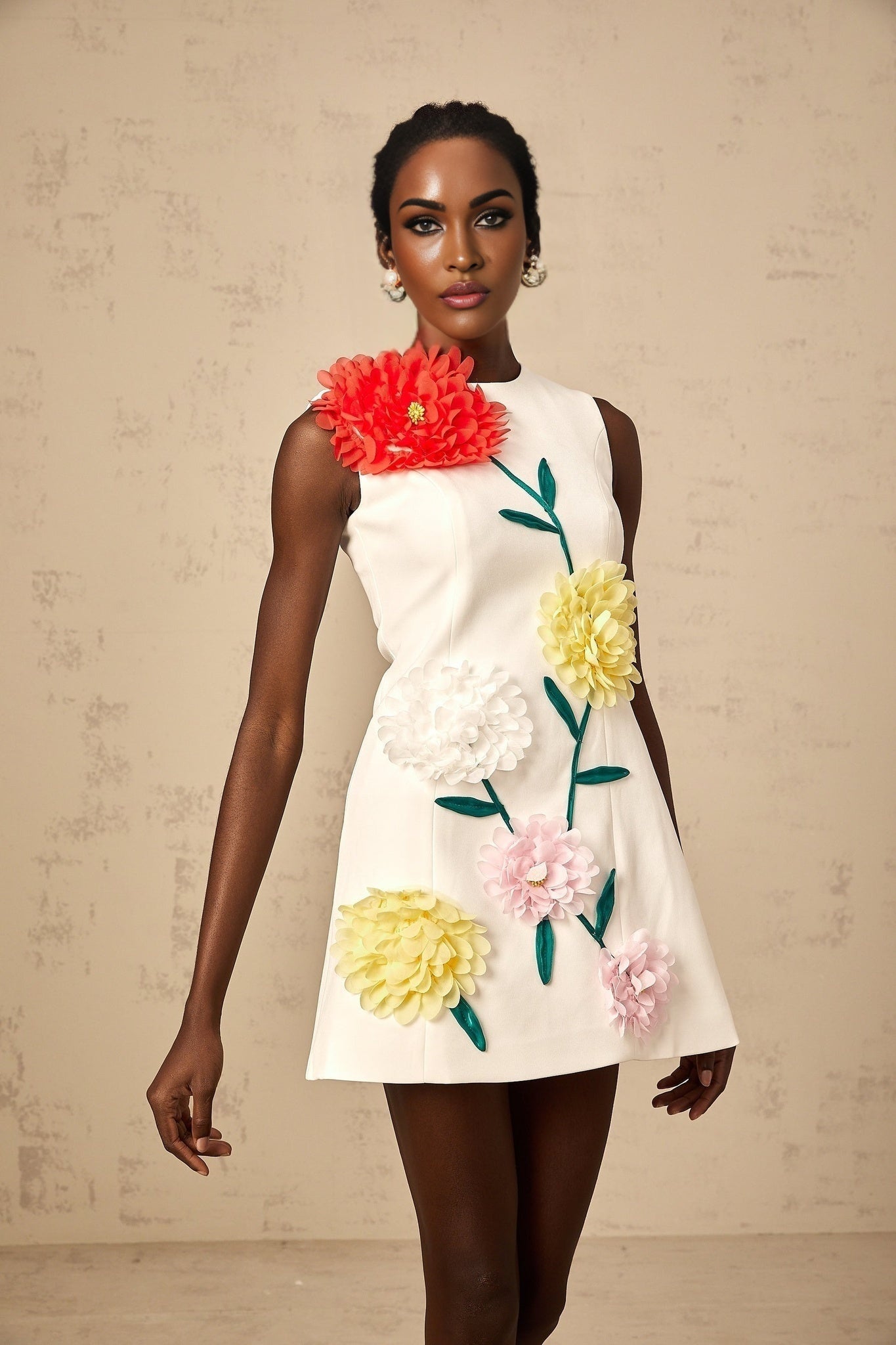 Woman wearing a sleeveless white mini dress with 3d floral petal details