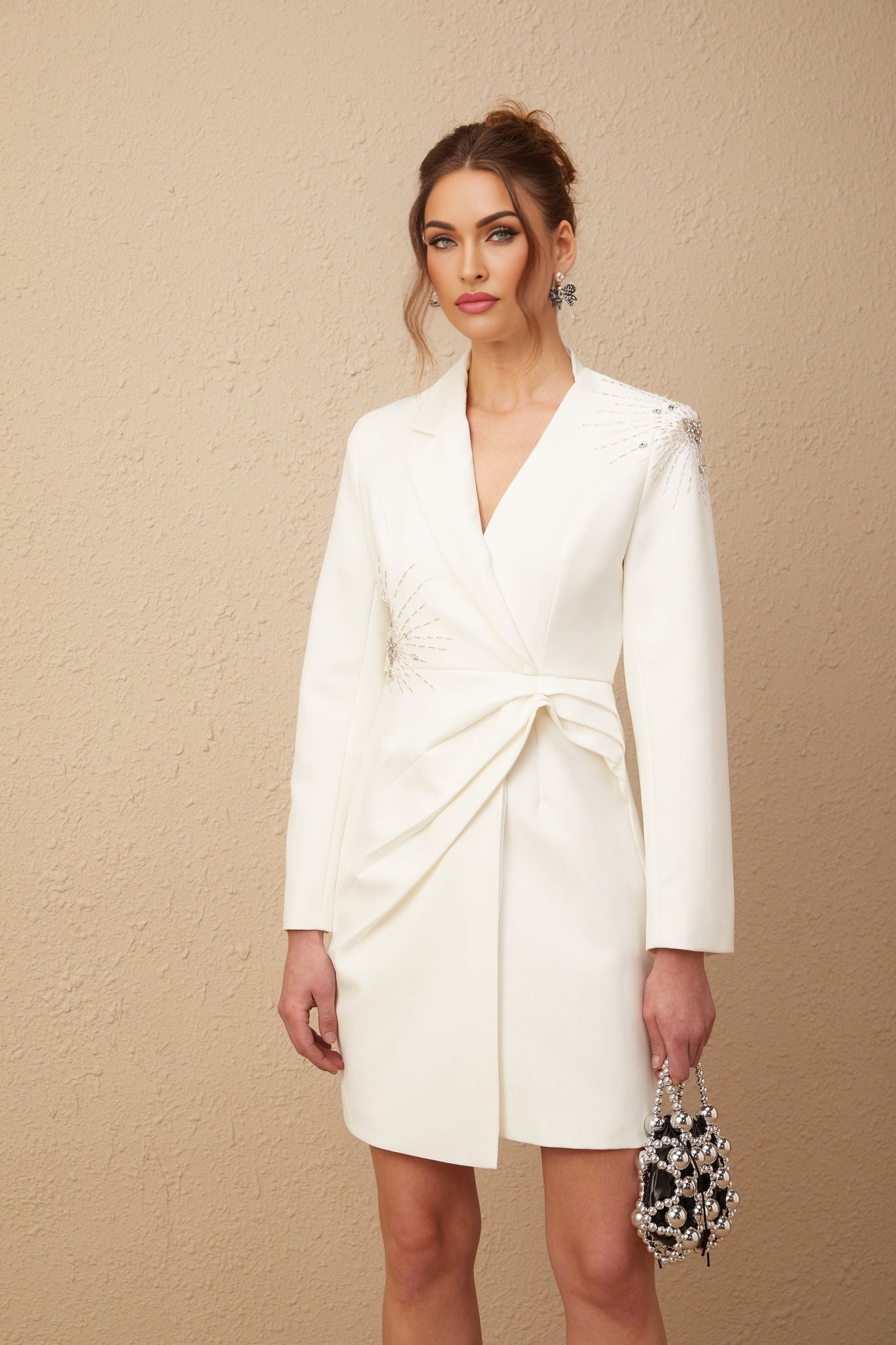 Woman wearing a white asymmetric blazer dress with embellishments