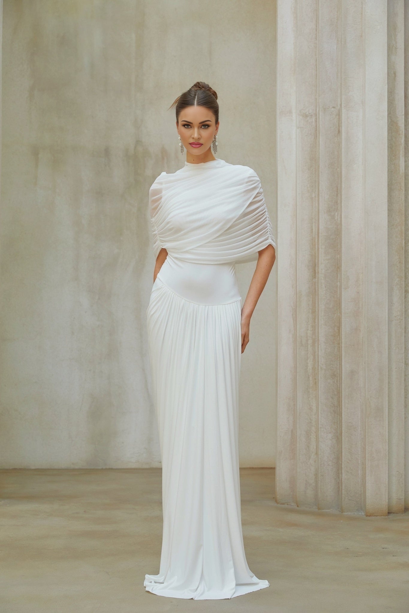 Woman wearing a white asymmetrical pleated maxi dress with flowing skirt and elegant design