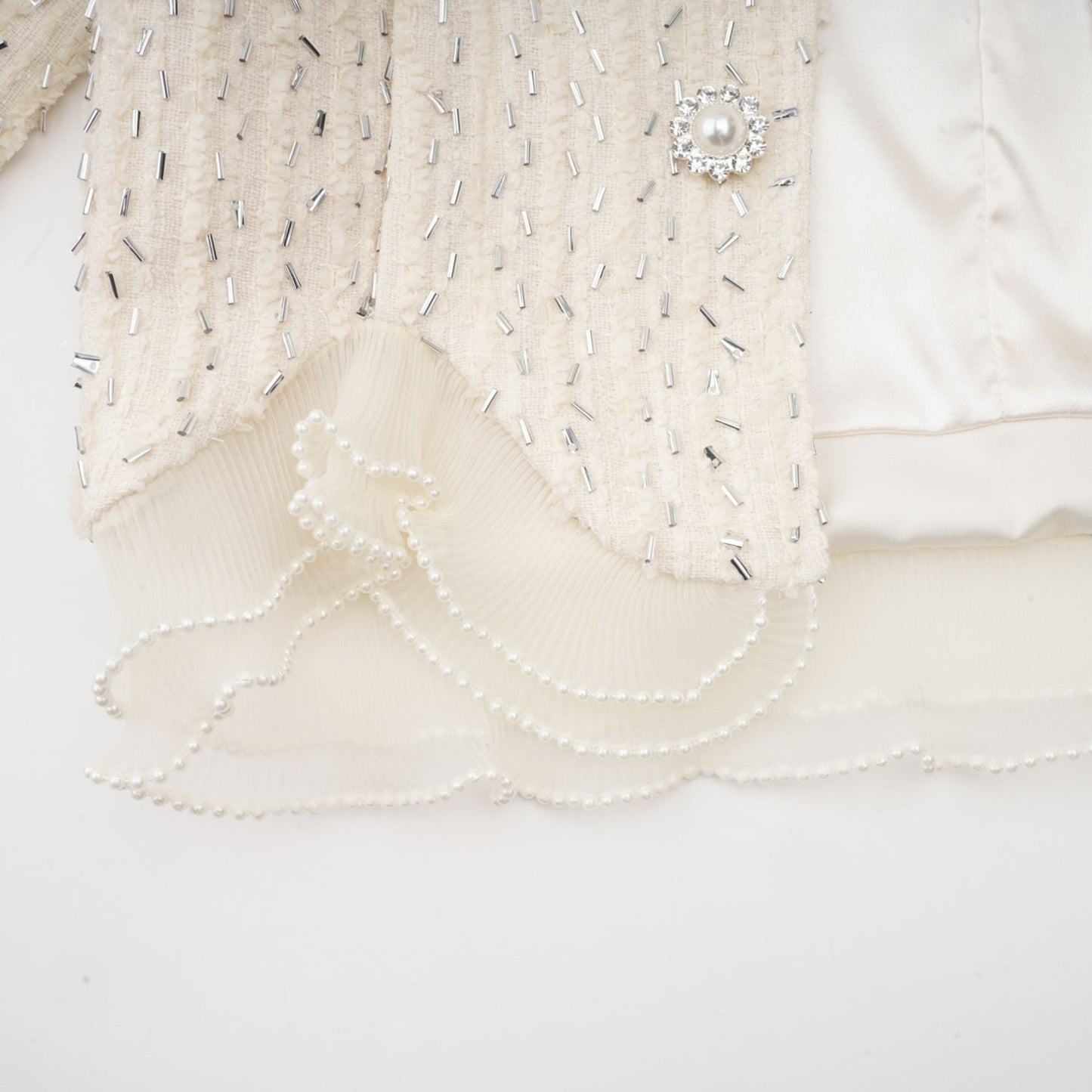 Woman wearing a white cropped jacket with beaded details and ruffle accents