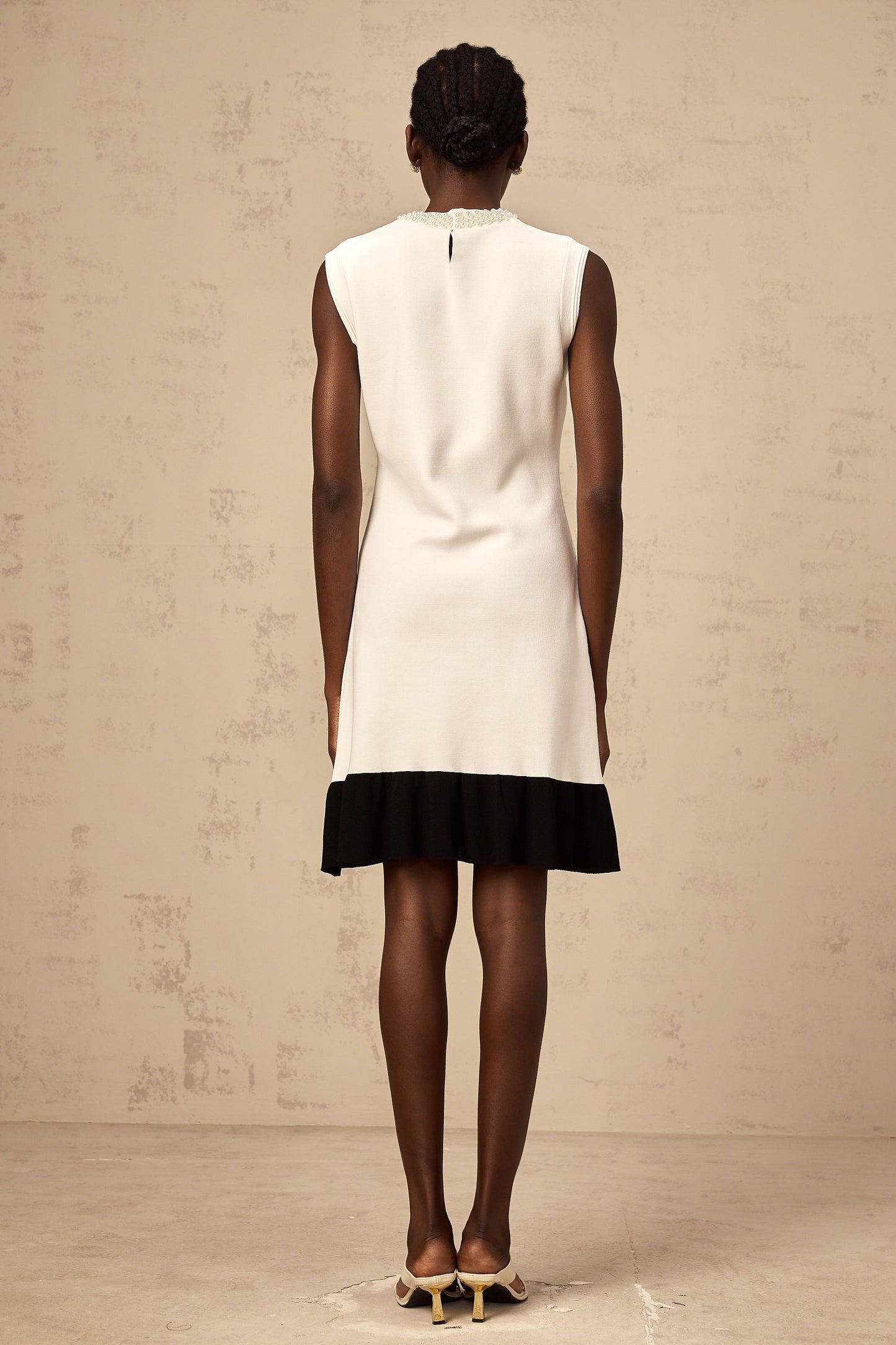 Woman wearing a white knitted cardigan adorned with faux pearl embellishments