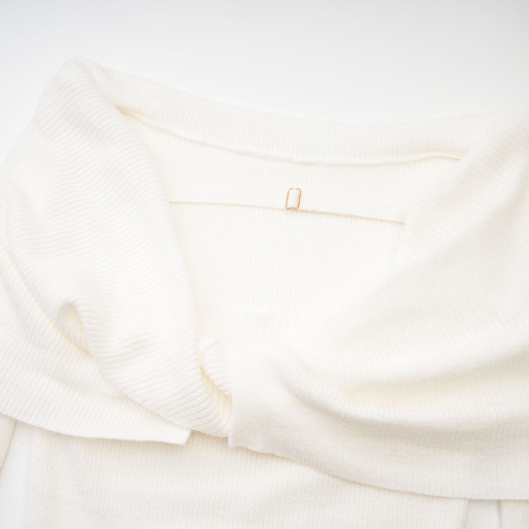 Woman wearing a white knitted strapless long sleeve top with textured pattern
